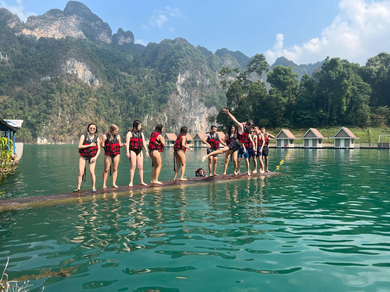 Students in life jackets line up on a floating dock at Cheow Lan Lake, surrounded by limestone cliffs
