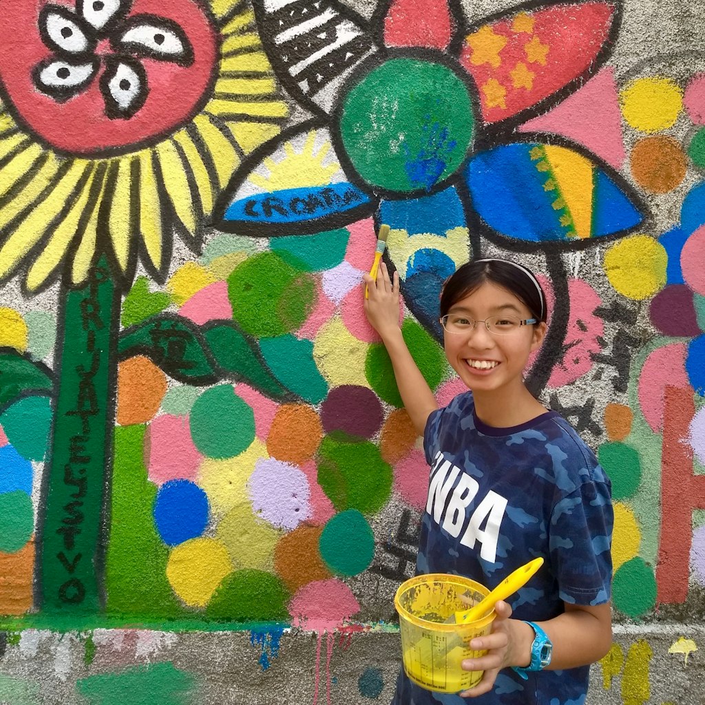 a smiling girl painting on the wall while thinking about cas trips
