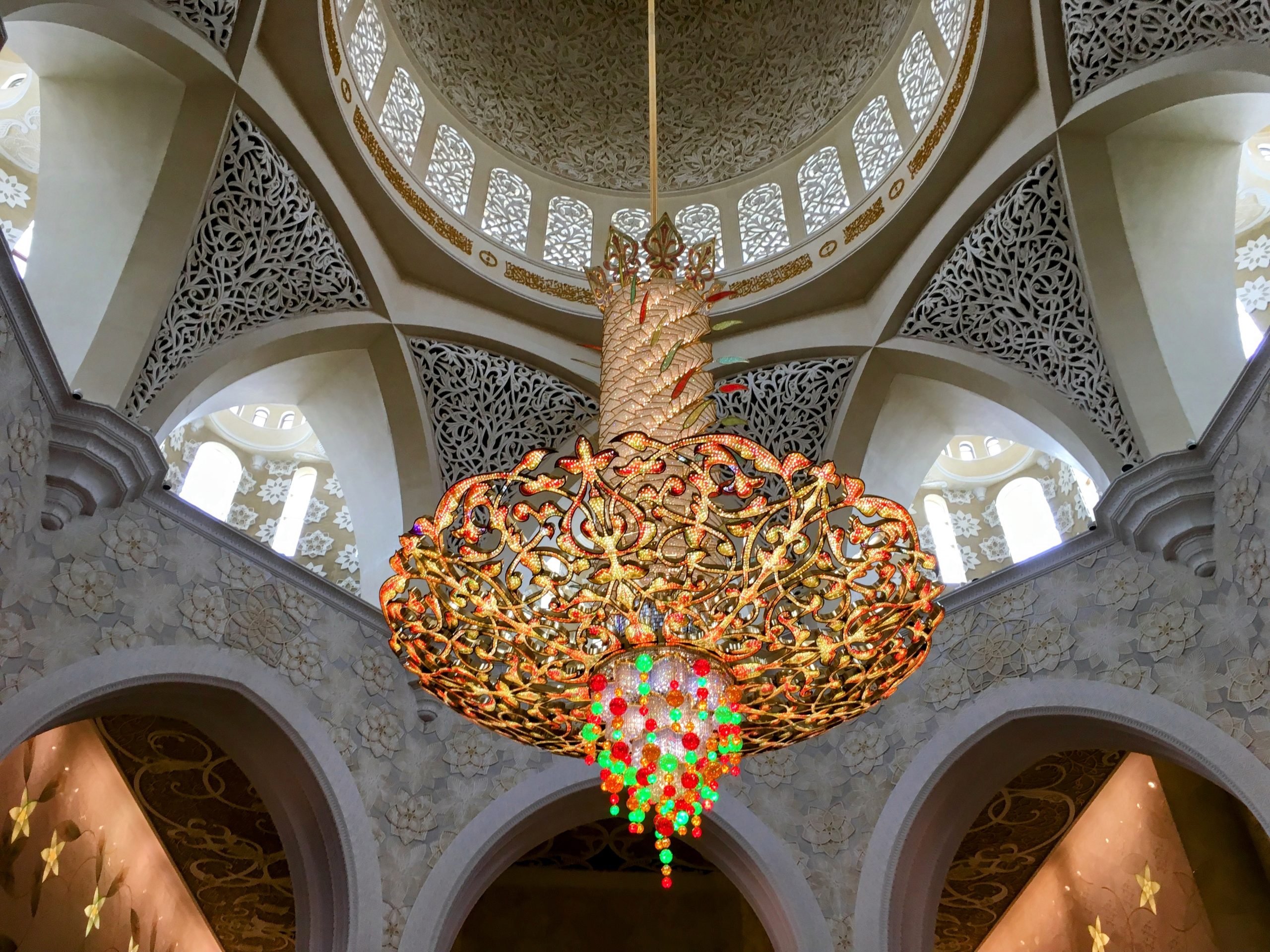 Ornate chandelier in the dome of Sheikh Zayed Grand Mosque, with intricate gold detailing and arches