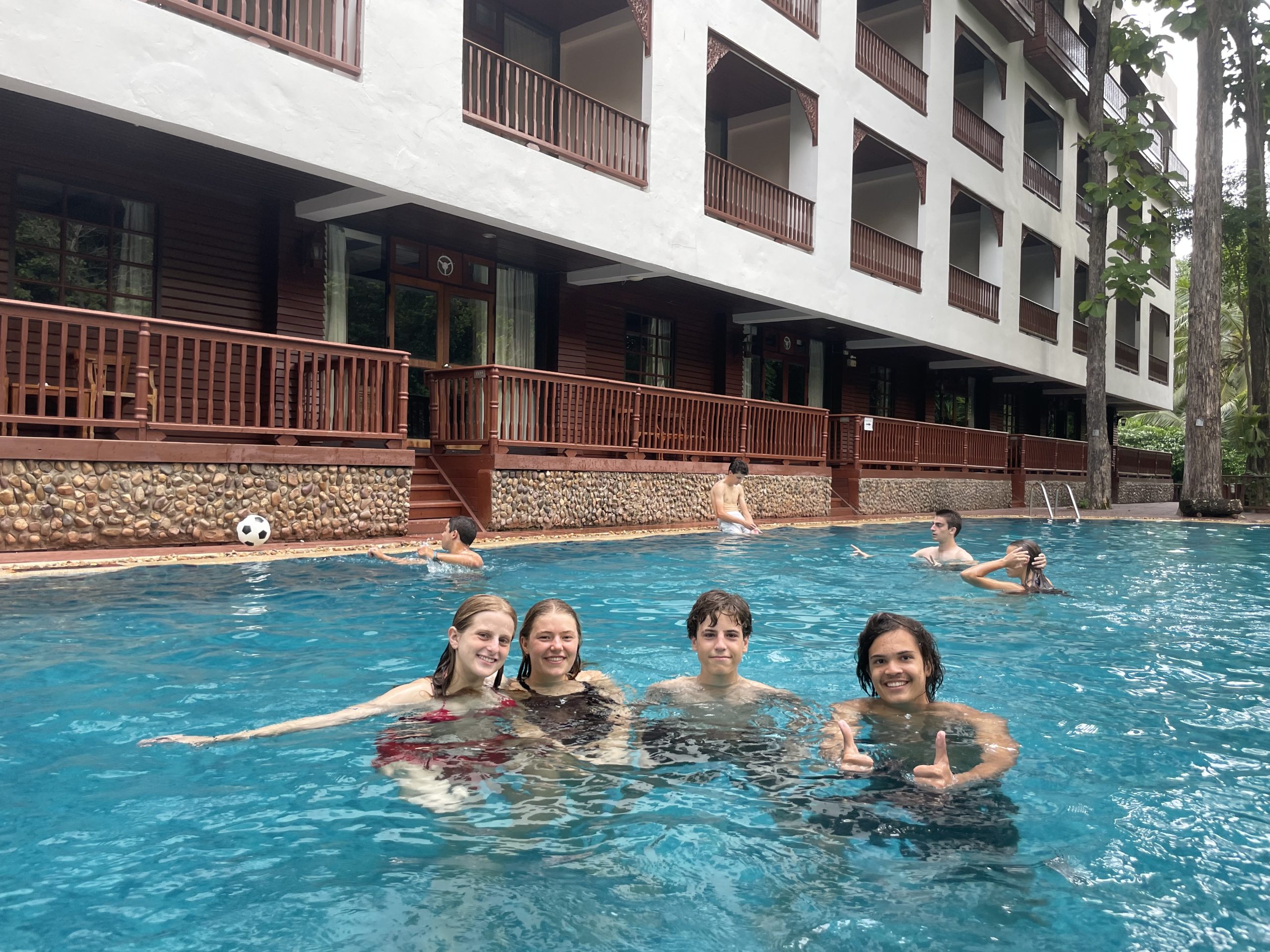 4 students swimming in the hotel pool