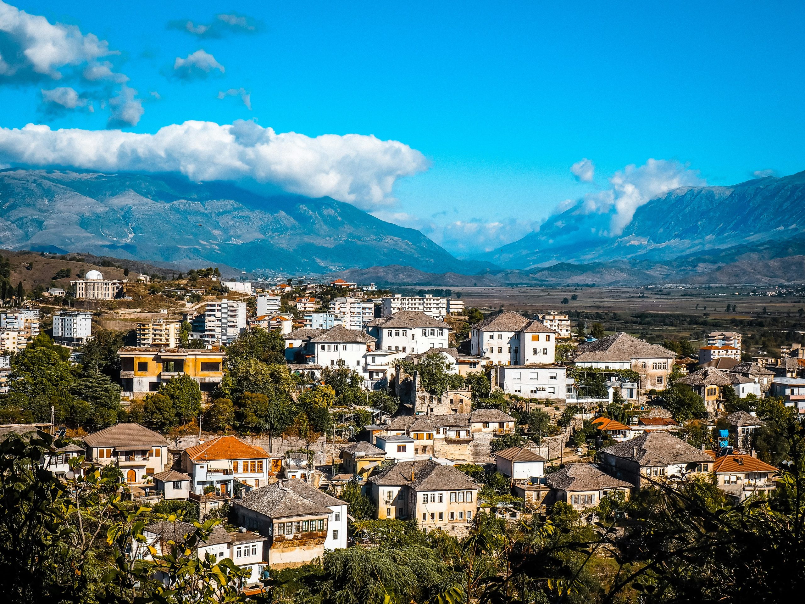 Stone-roofed houses of Gjirokaster's old town, with the valley and mountains beyond, in southern Albania.