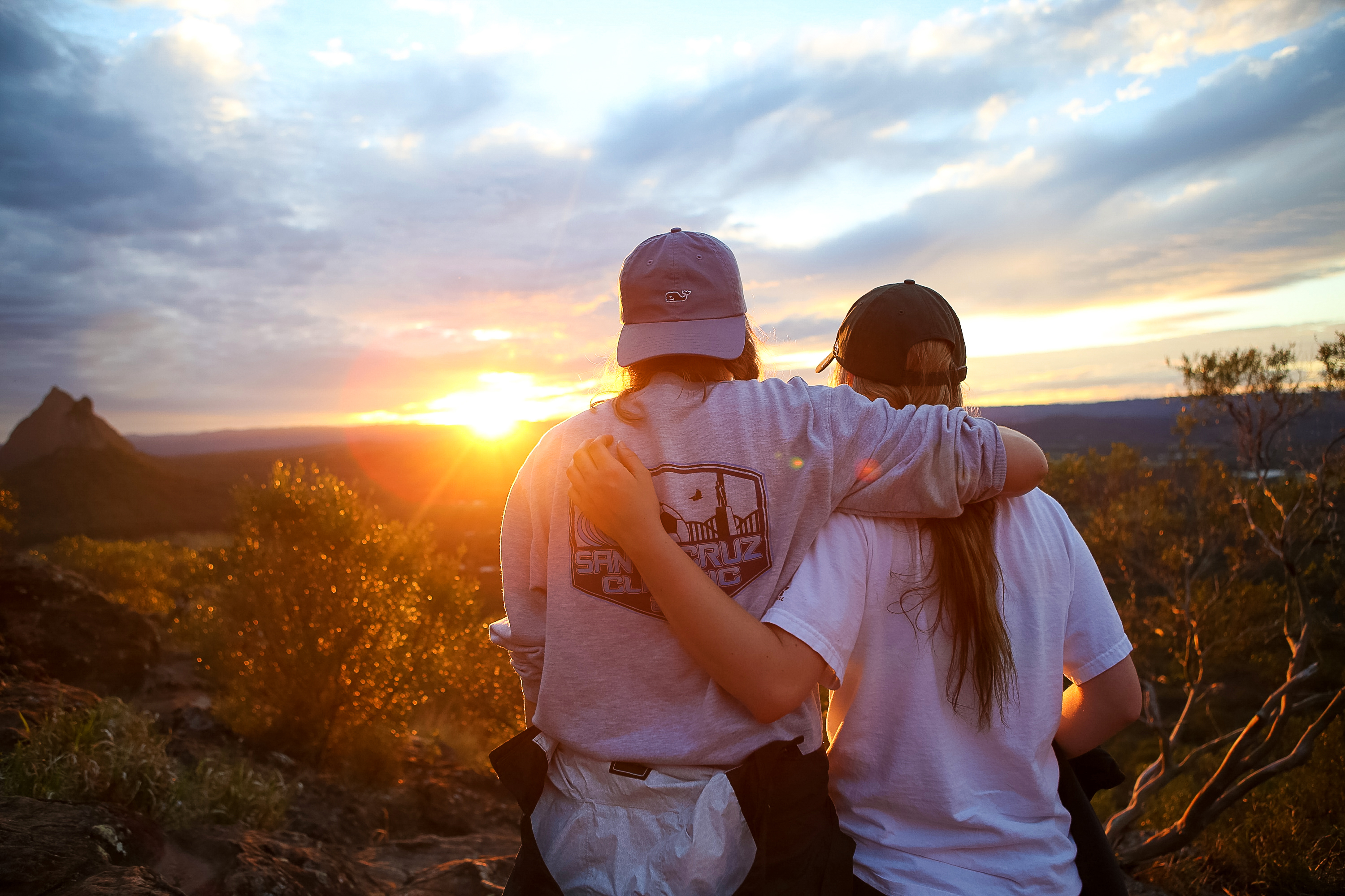 Student travelers embrace while watching the sunset from a hilltop
