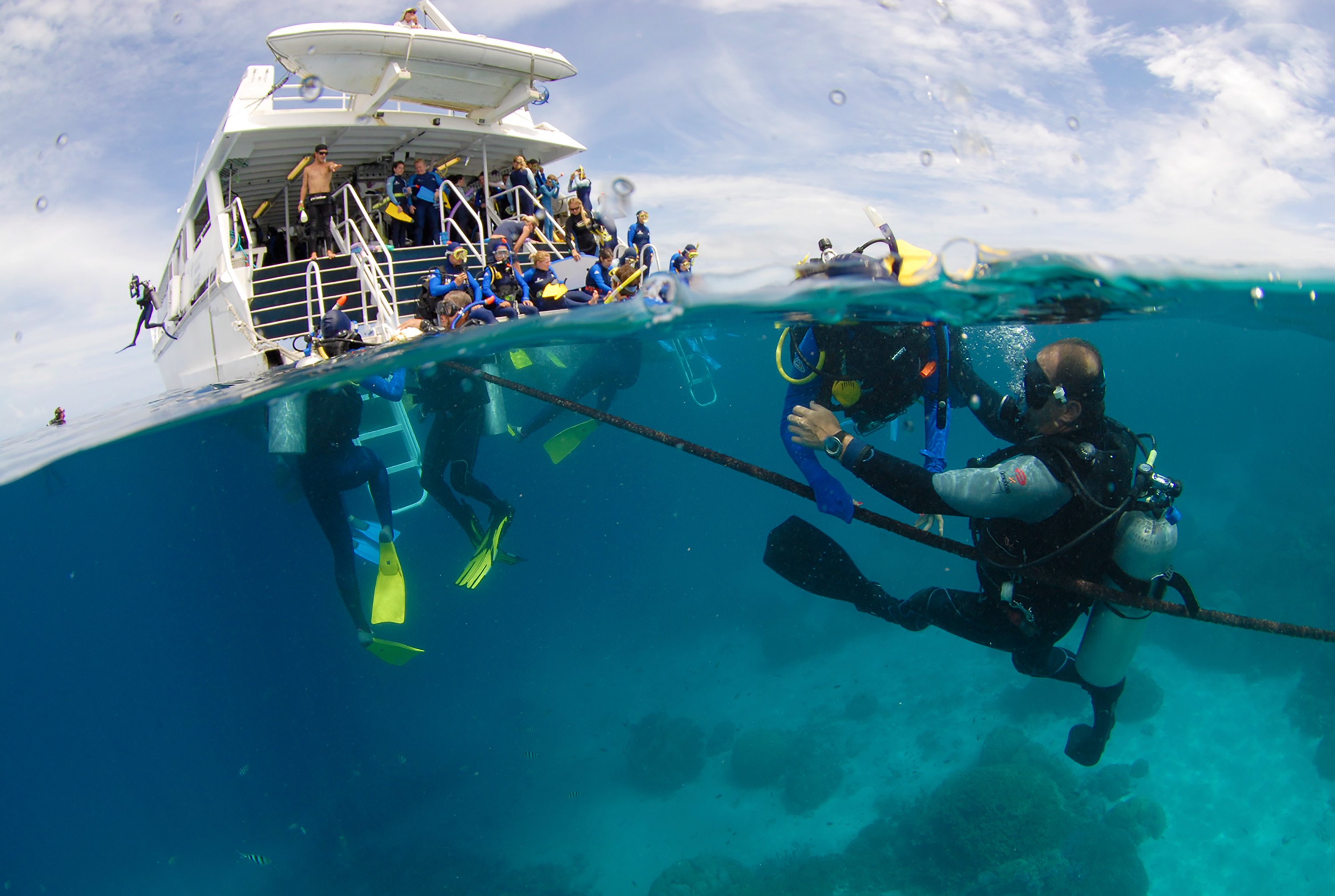 Student travelers descend from a dive boat over the Great Barrier Reef