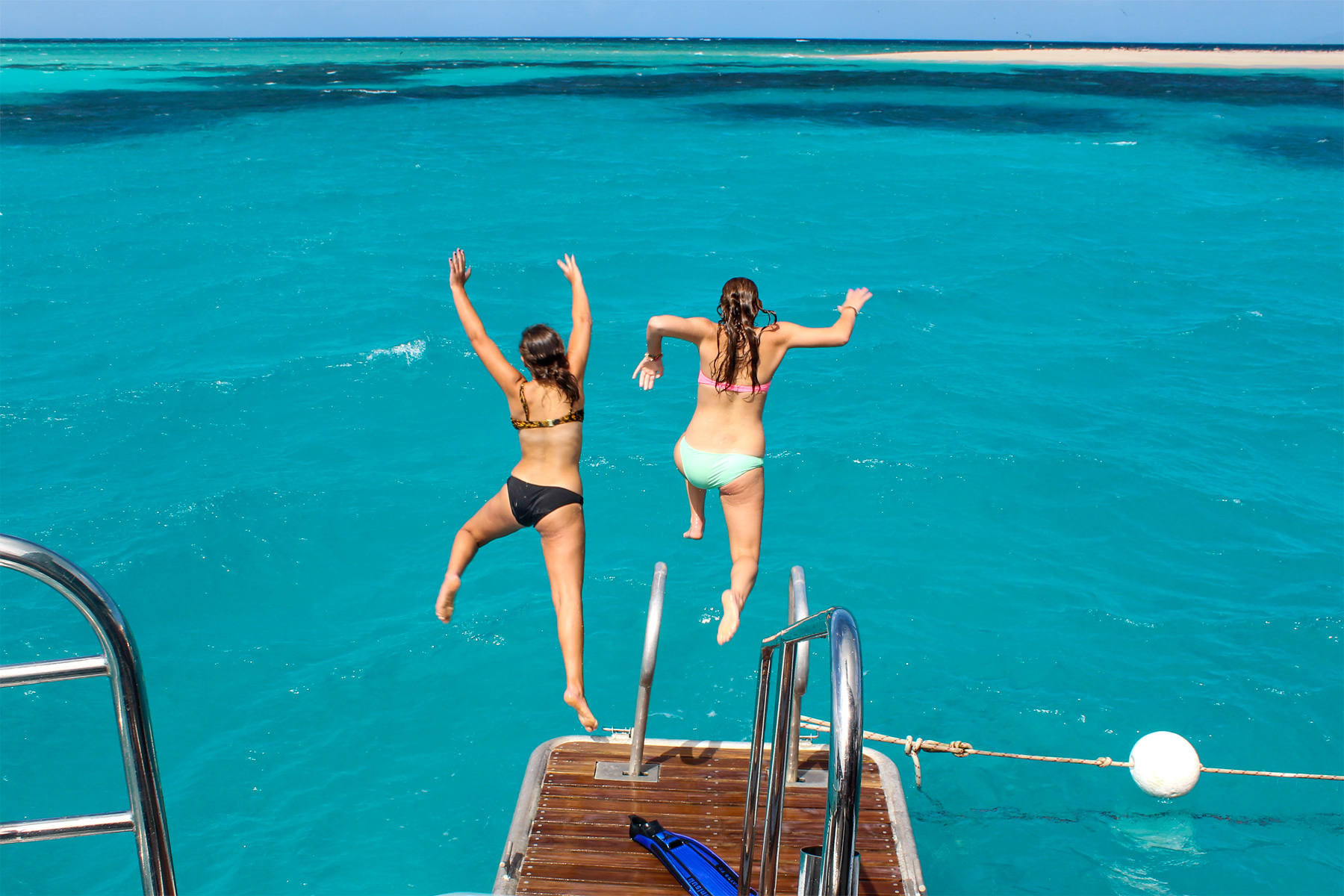 fun facts about australia. Two women jumping off a boat into the turquoise sea.