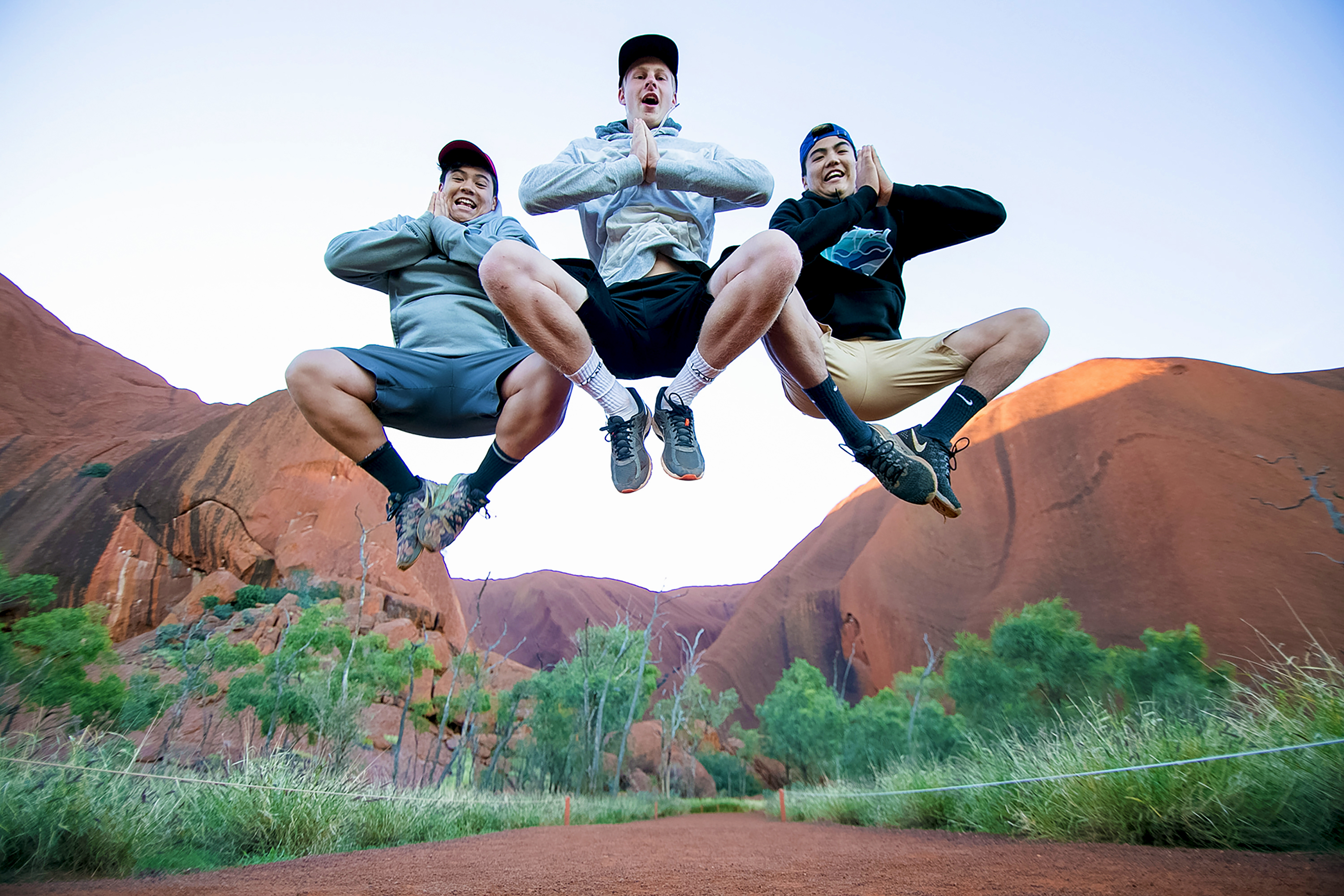 Students jump for joy in front of Uluru's red rock formations in Australia
