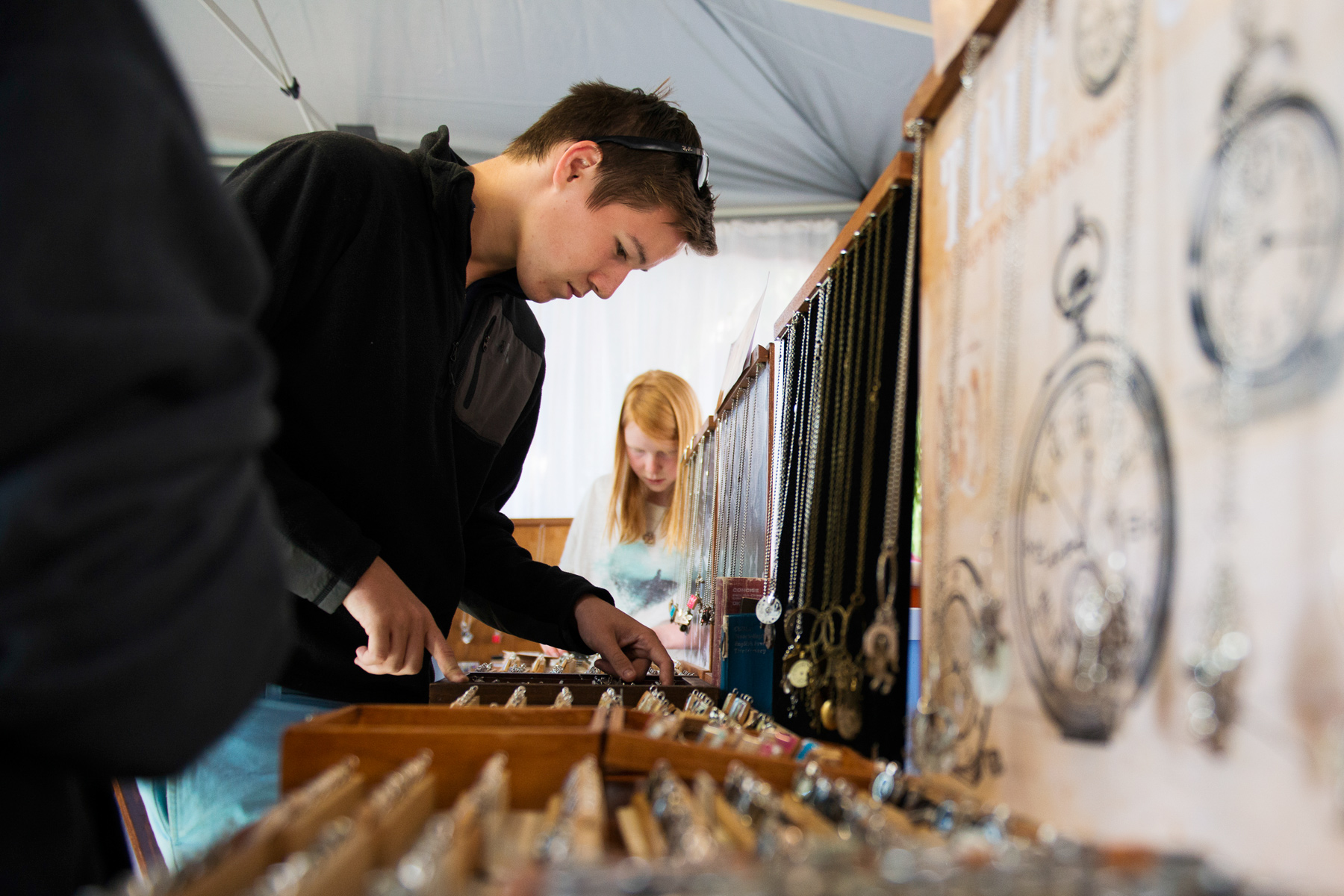 A student looks over trays of pendants and jewellery at a market stall