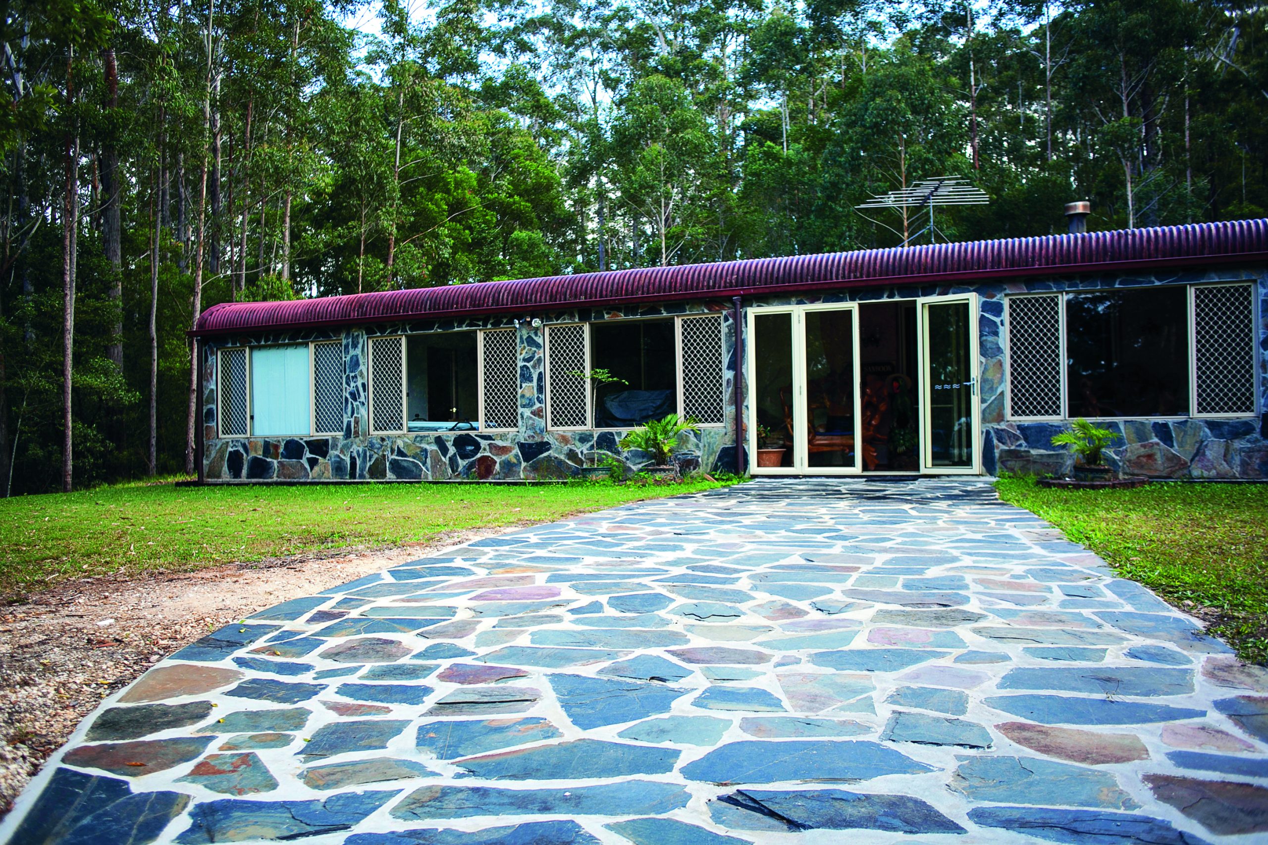 A long stone-paved path leads to a low timber field station in the bush