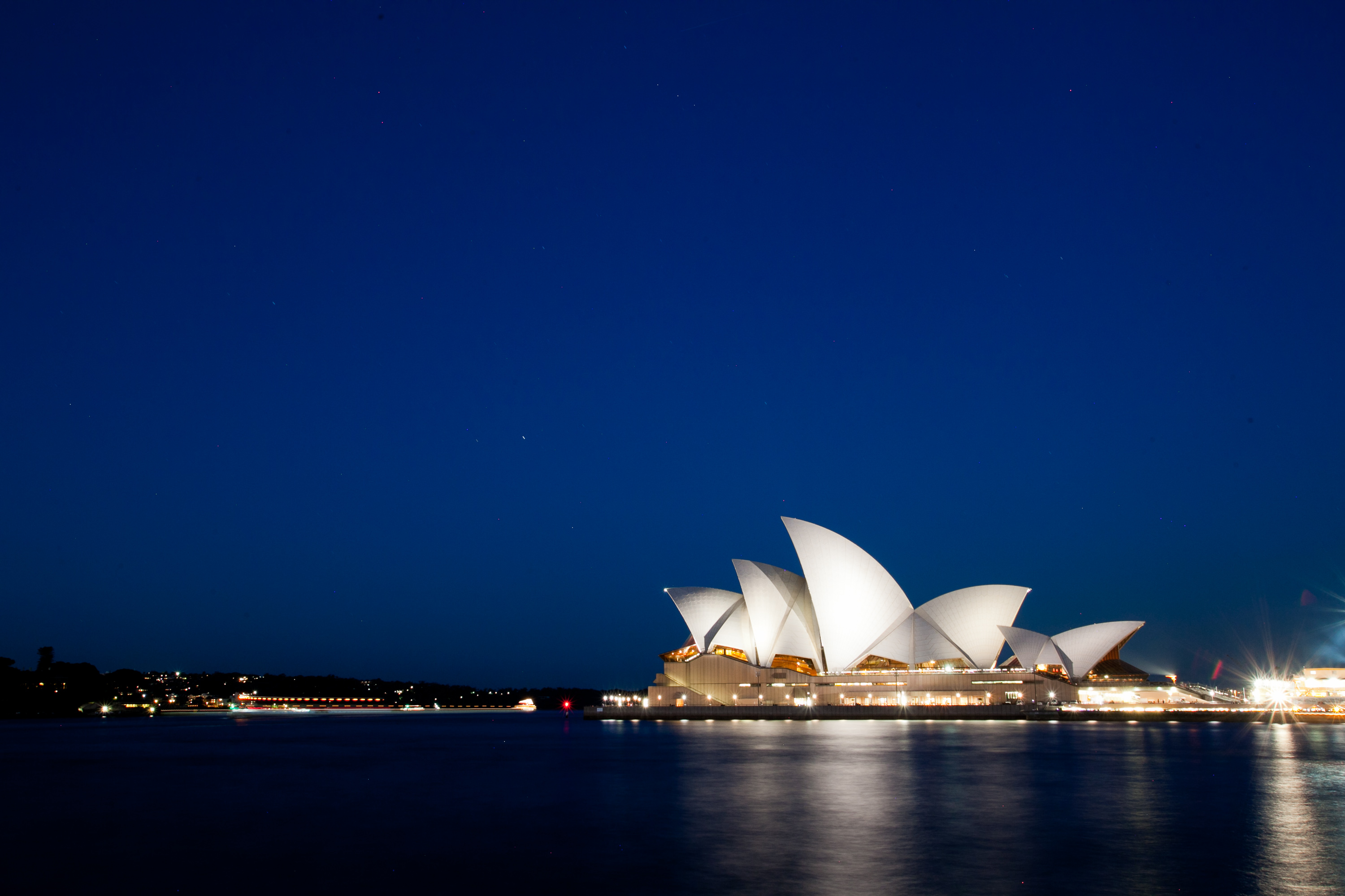 The Sydney Opera House lit at dusk with the harbour dark in the foreground