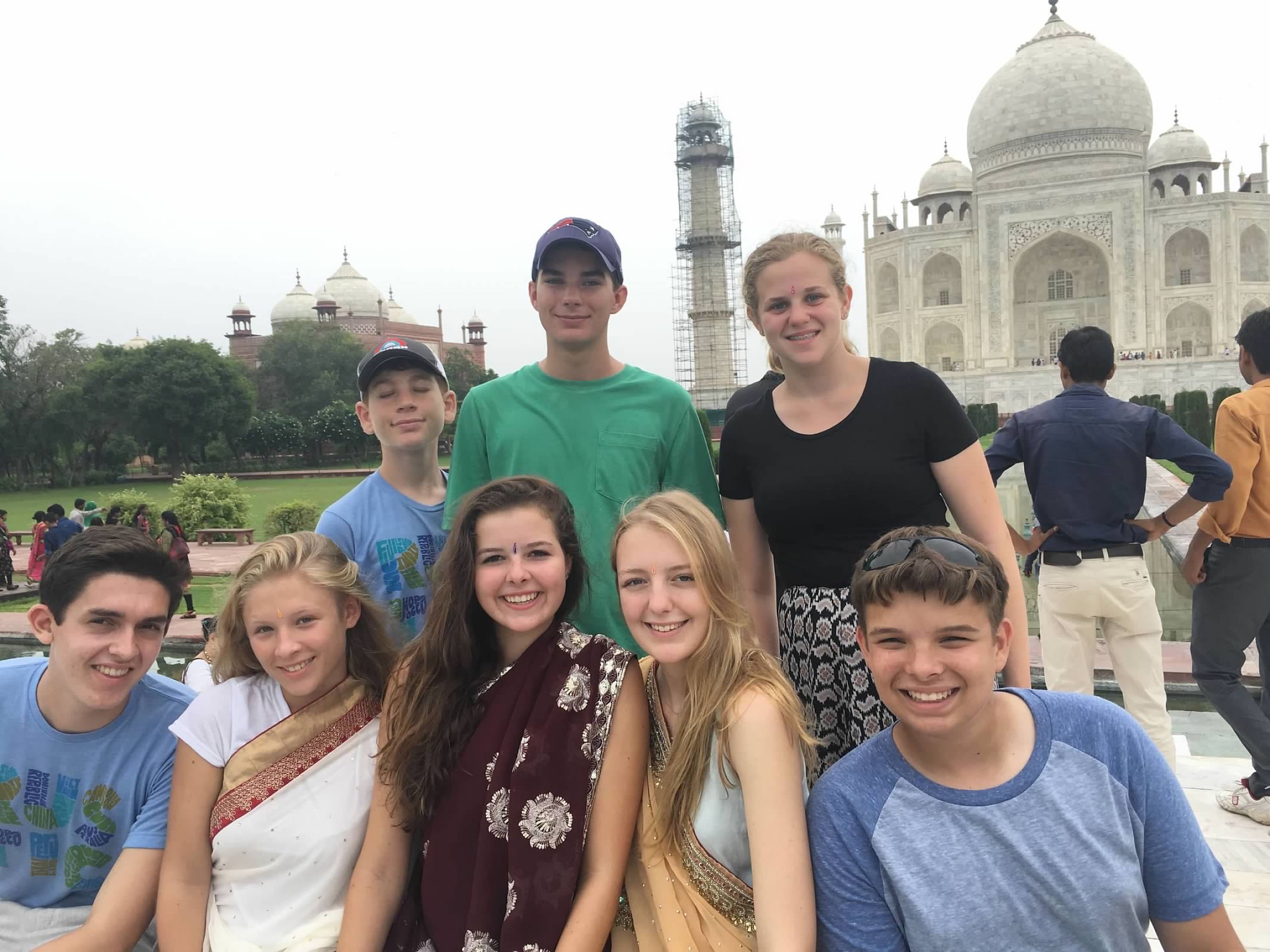 Group of young people posing in front of the Taj Mahal.