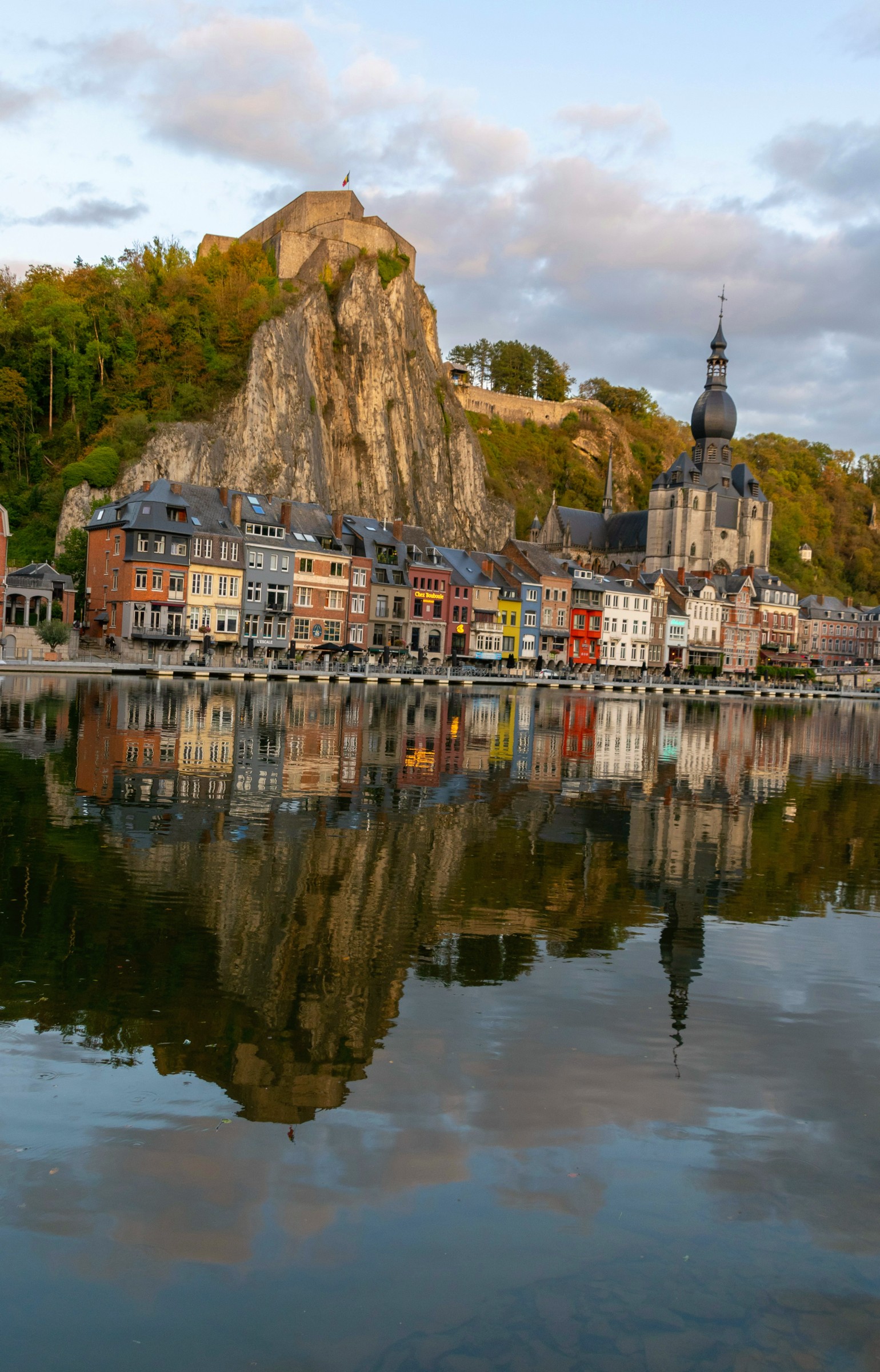 A rocky bluff topped by a citadel above a church dome, reflected in the river below.