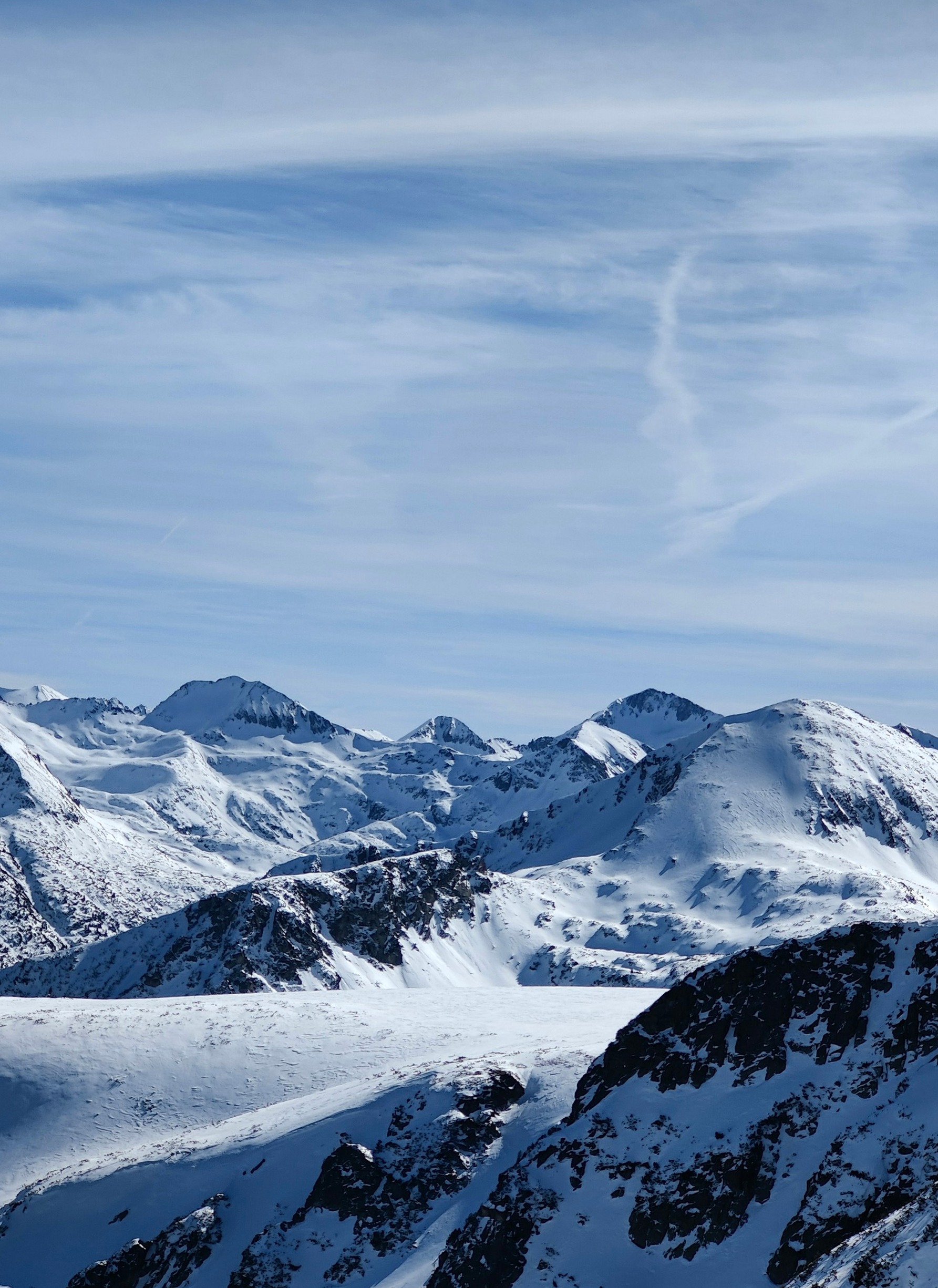 Snow-covered peaks of the Pirin range under a pale winter sky, seen from the Bansko ski area.