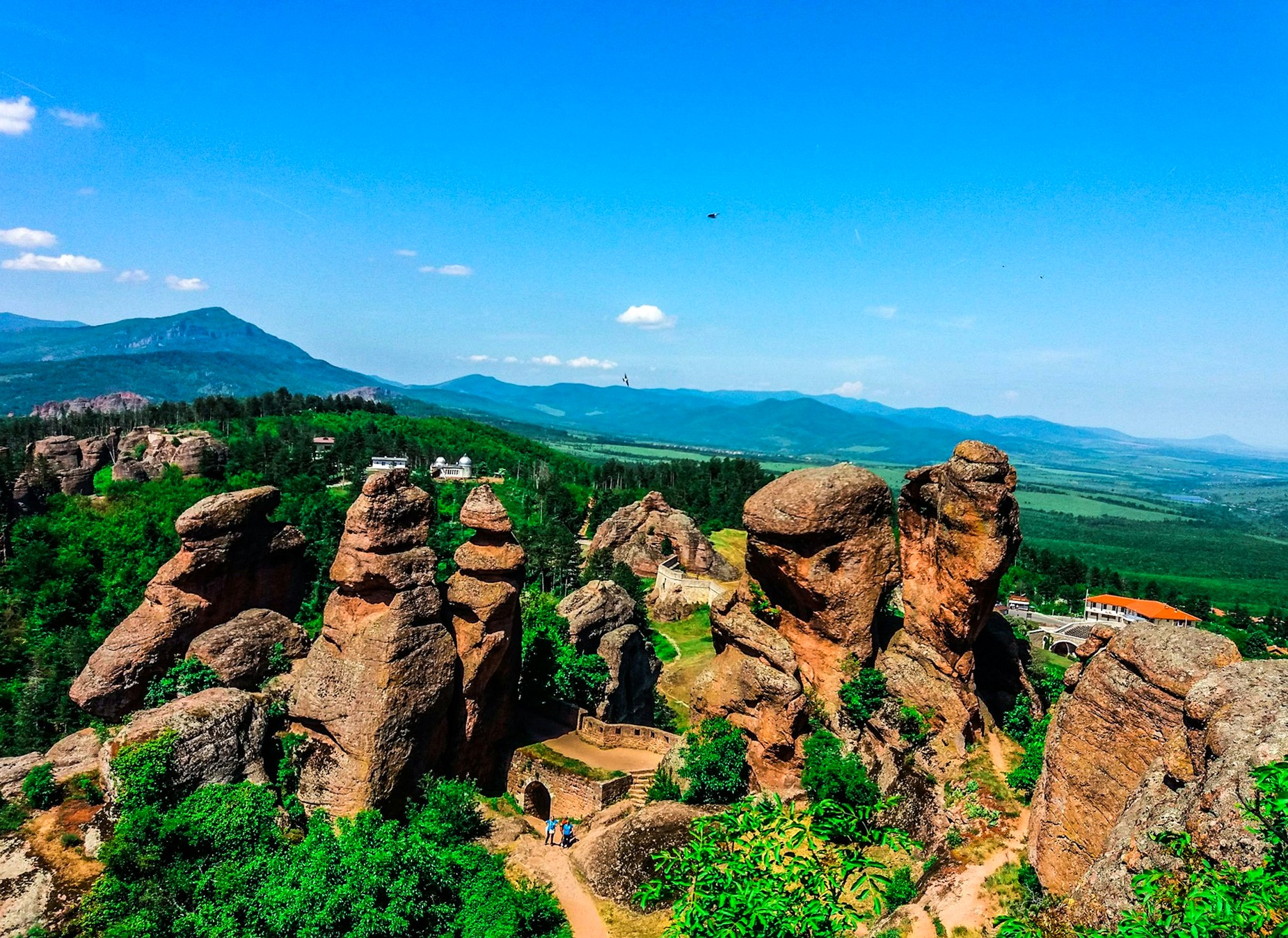 Red sandstone towers of the Belogradchik Rocks rise above wooded hills in northwestern Bulgaria.
