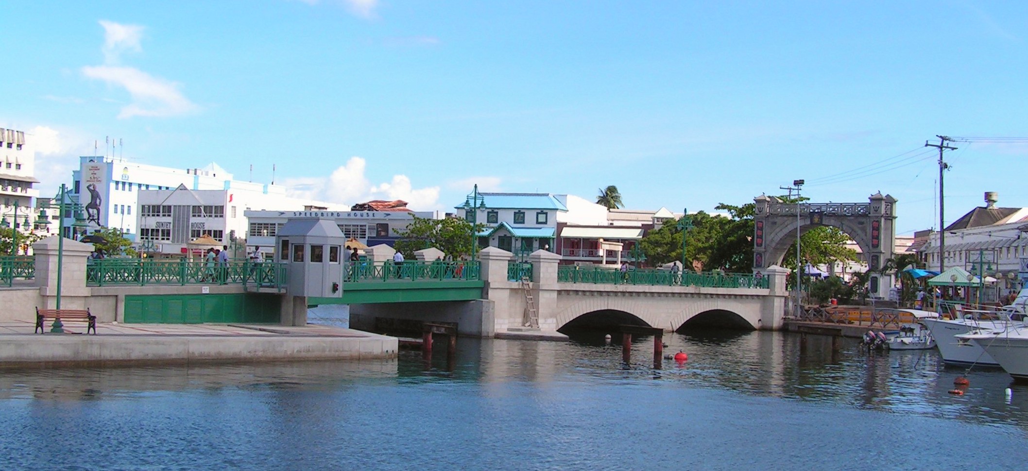 Chamberlain Bridge over the Careenage in Bridgetown, with the Parliament clock tower and moored boats behind it.