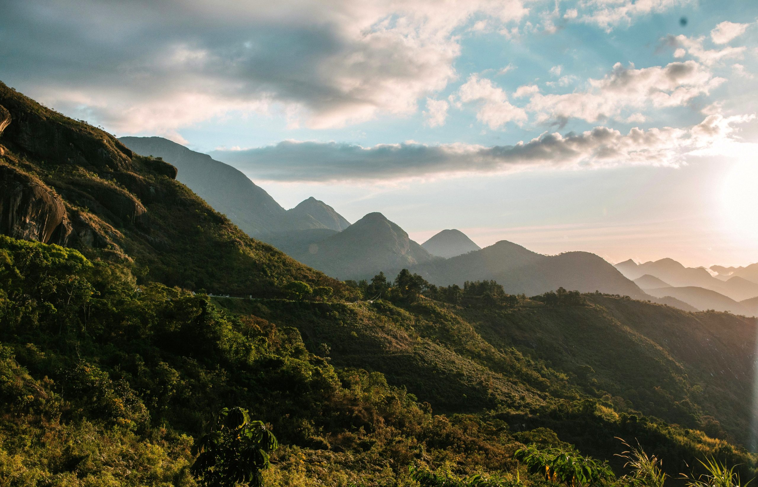 Forested hills around Petrópolis at golden hour, ridgelines receding into haze toward the coast.