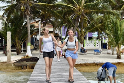 Two teens smile and walk hand in hand on a boardwalk in Belize during a teen tour in the americas