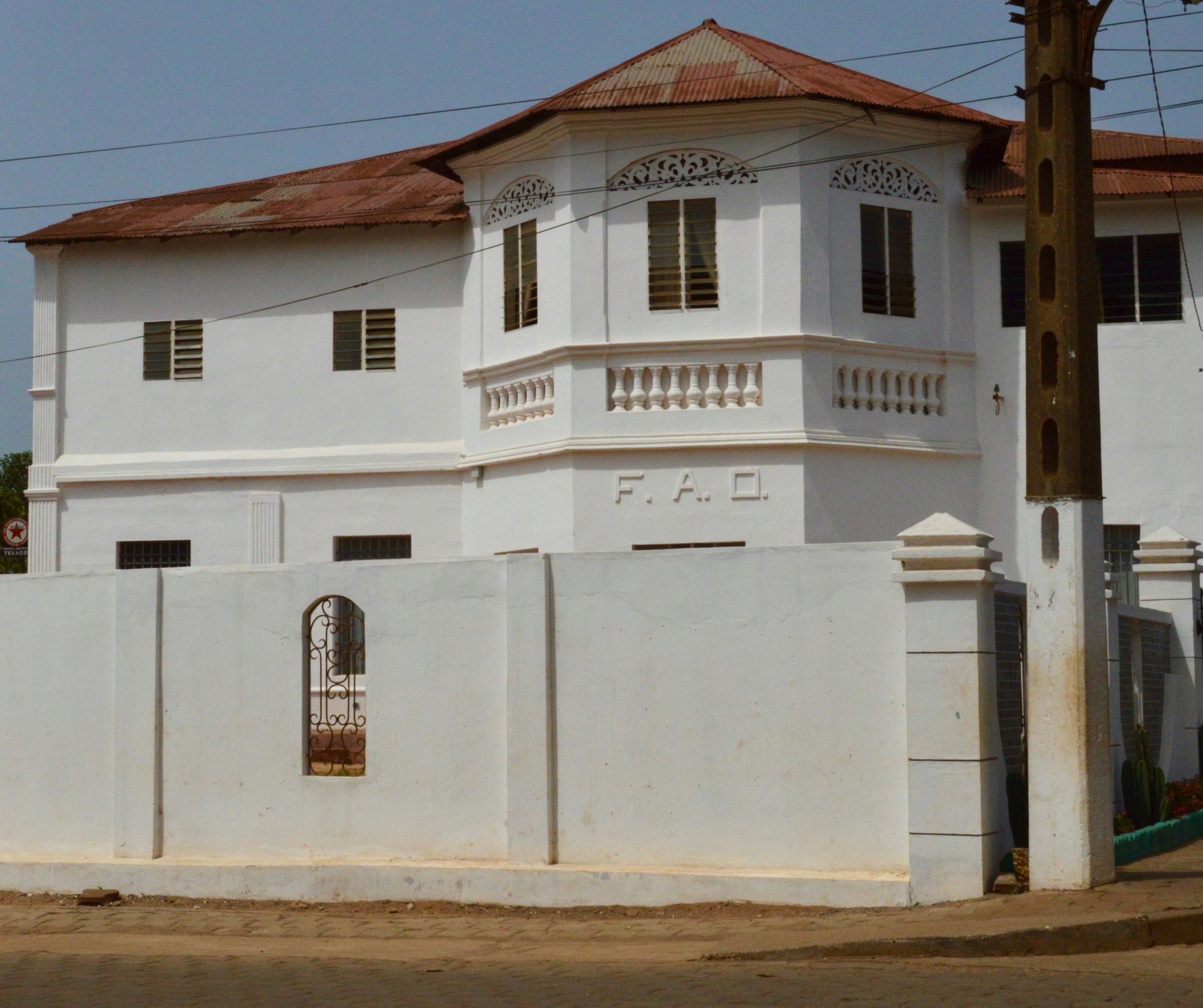 A colonial-style building in Benin with white walls, intricate detailing, and a red roof, representing historical architecture.