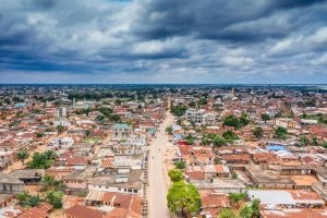 An aerial view of Cotonou, Benin’s largest city, highlighting its dense urban landscape with red-roofed buildings under cloudy skies.
