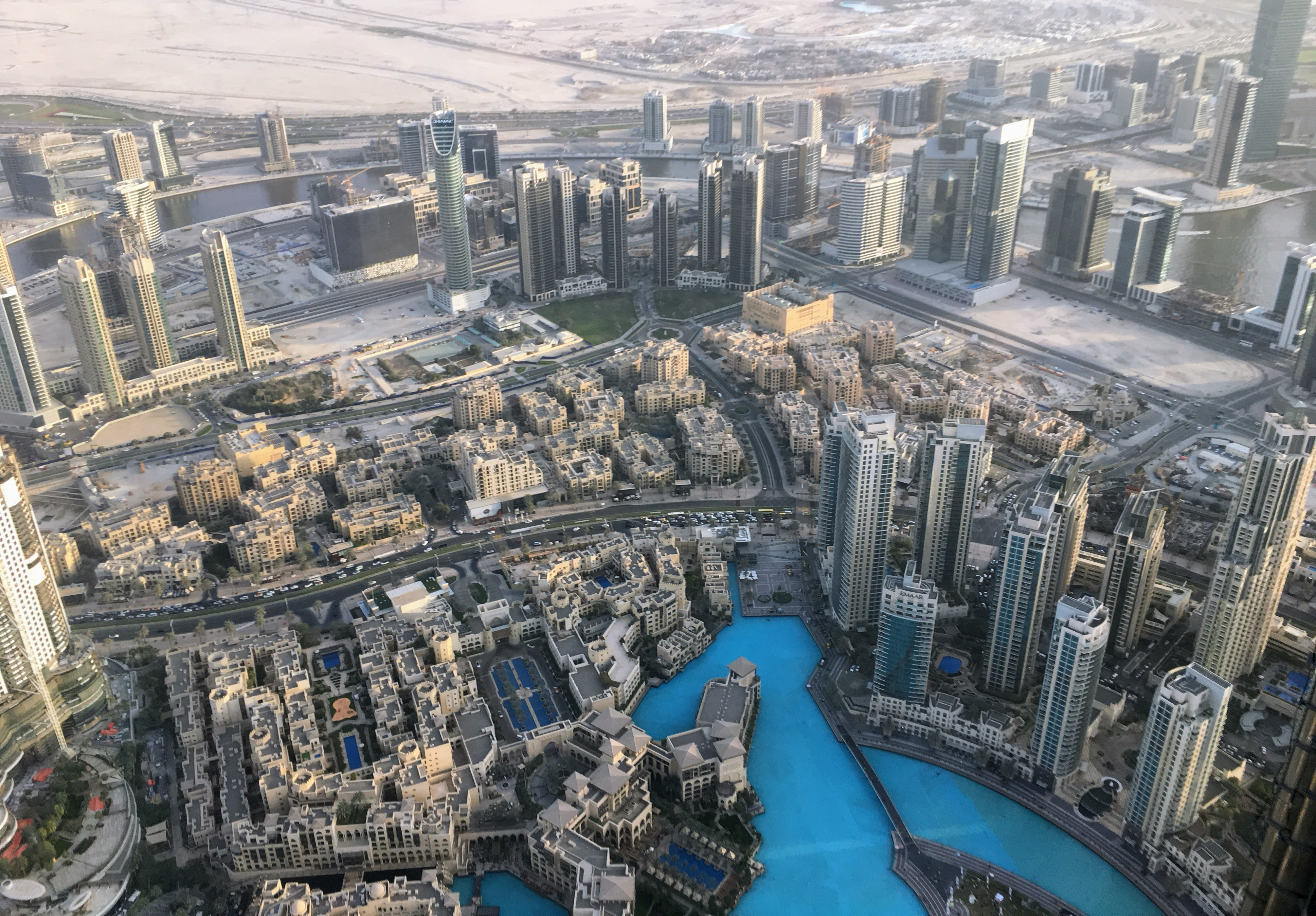 Aerial view of downtown Dubai, featuring high-rise buildings, blue water canals, and sprawling cityscape