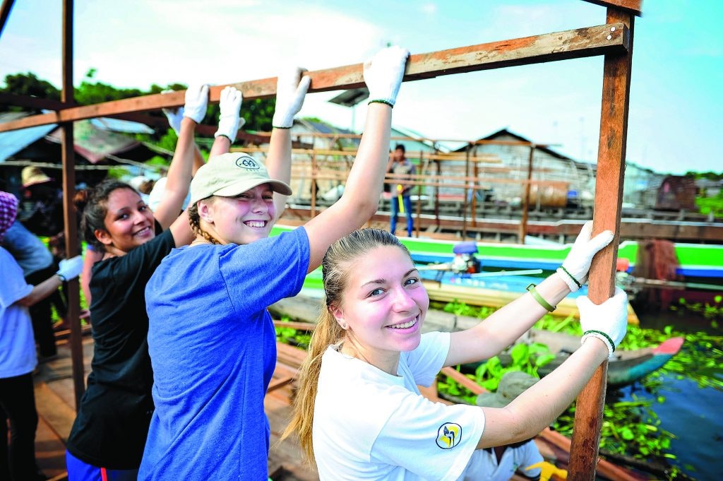 Rustic Pathways students work together on a building project in a Cambodian floating village.