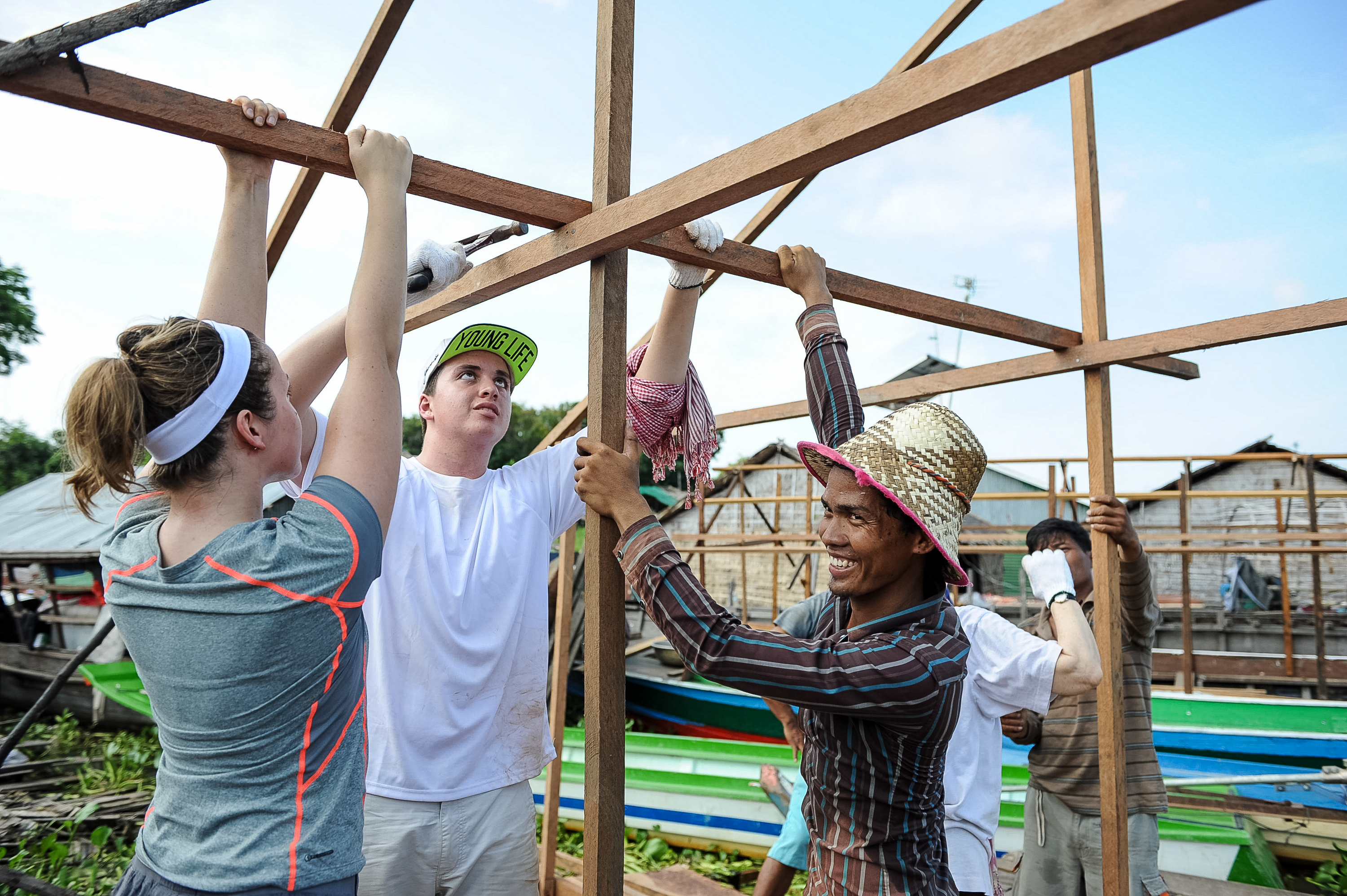 Students and a local resident raise wooden beams while building a frame structure