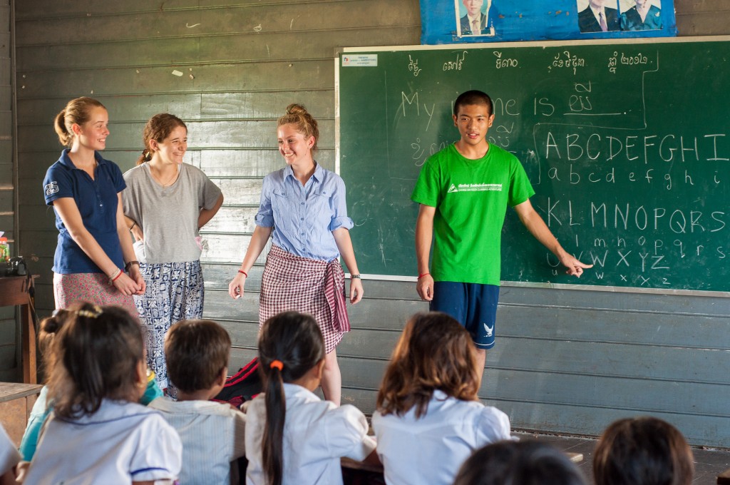 Students lead an English lesson at a chalkboard for local schoolchildren