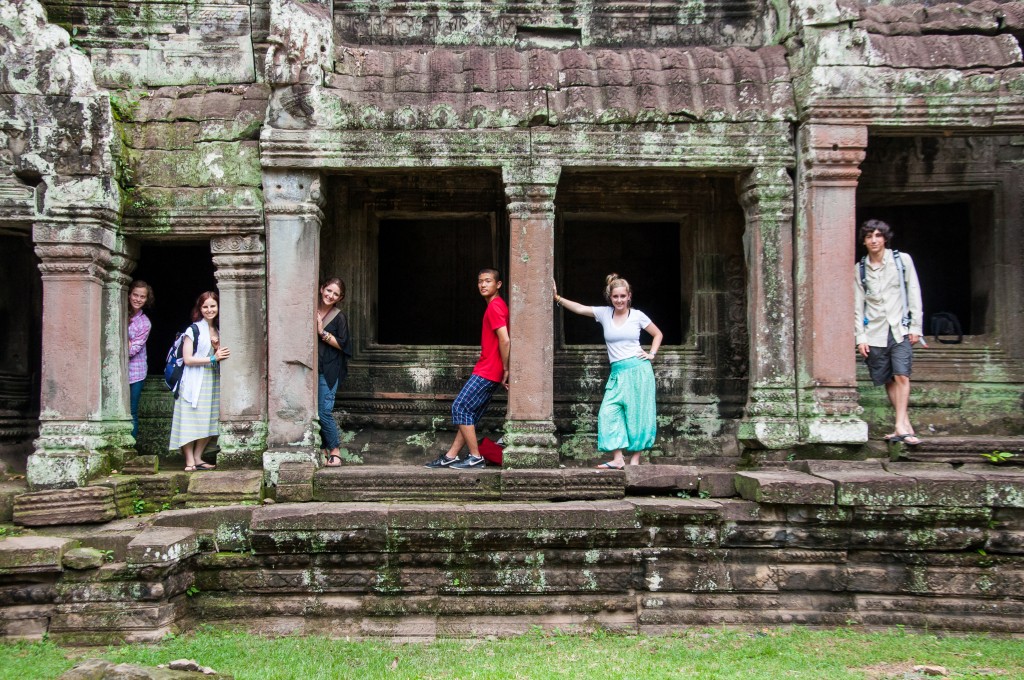 A school trip explores stone doorways and carved pillars of an ancient Angkor temple