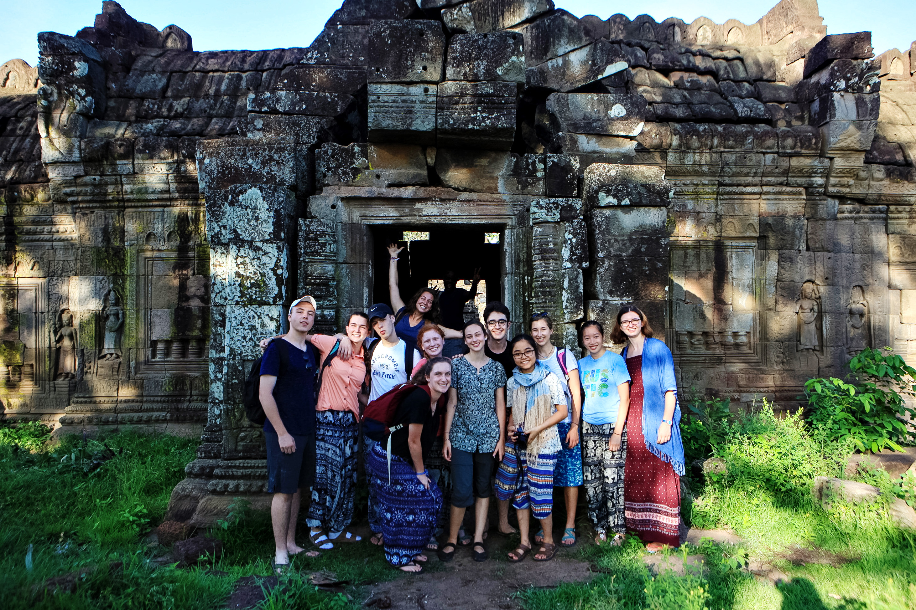A school group stands together in the doorway of an ancient stone temple in Cambodia.
