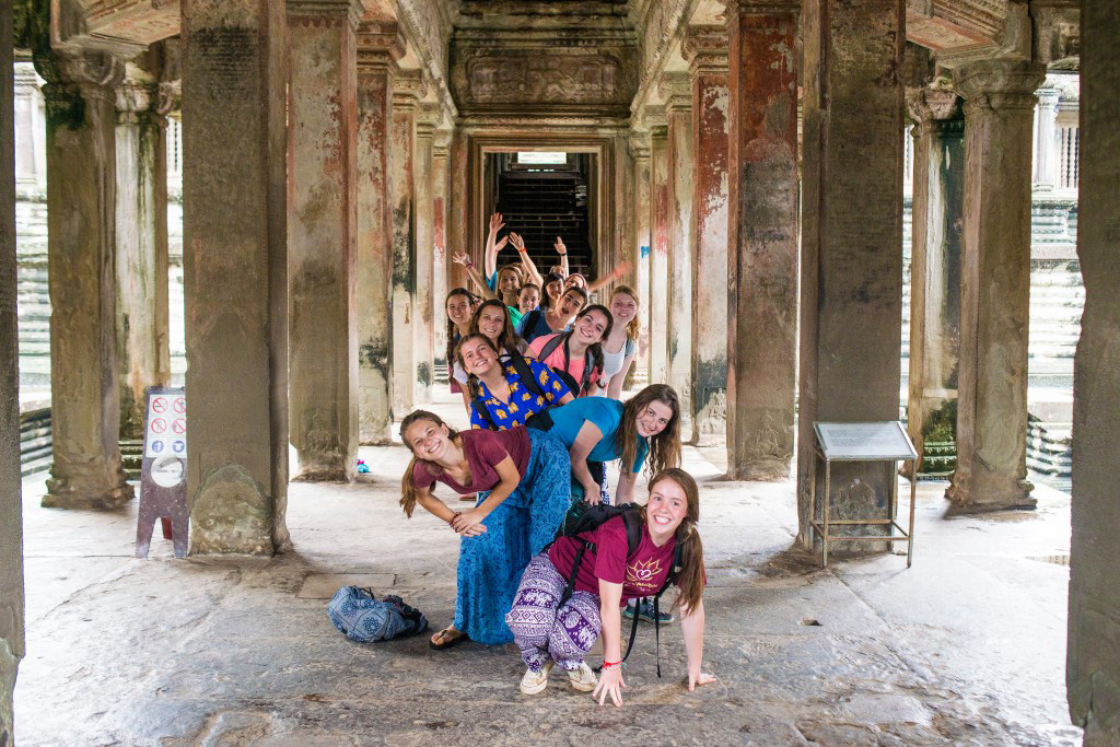 Students pose playfully among the stone columns of Angkor Wat