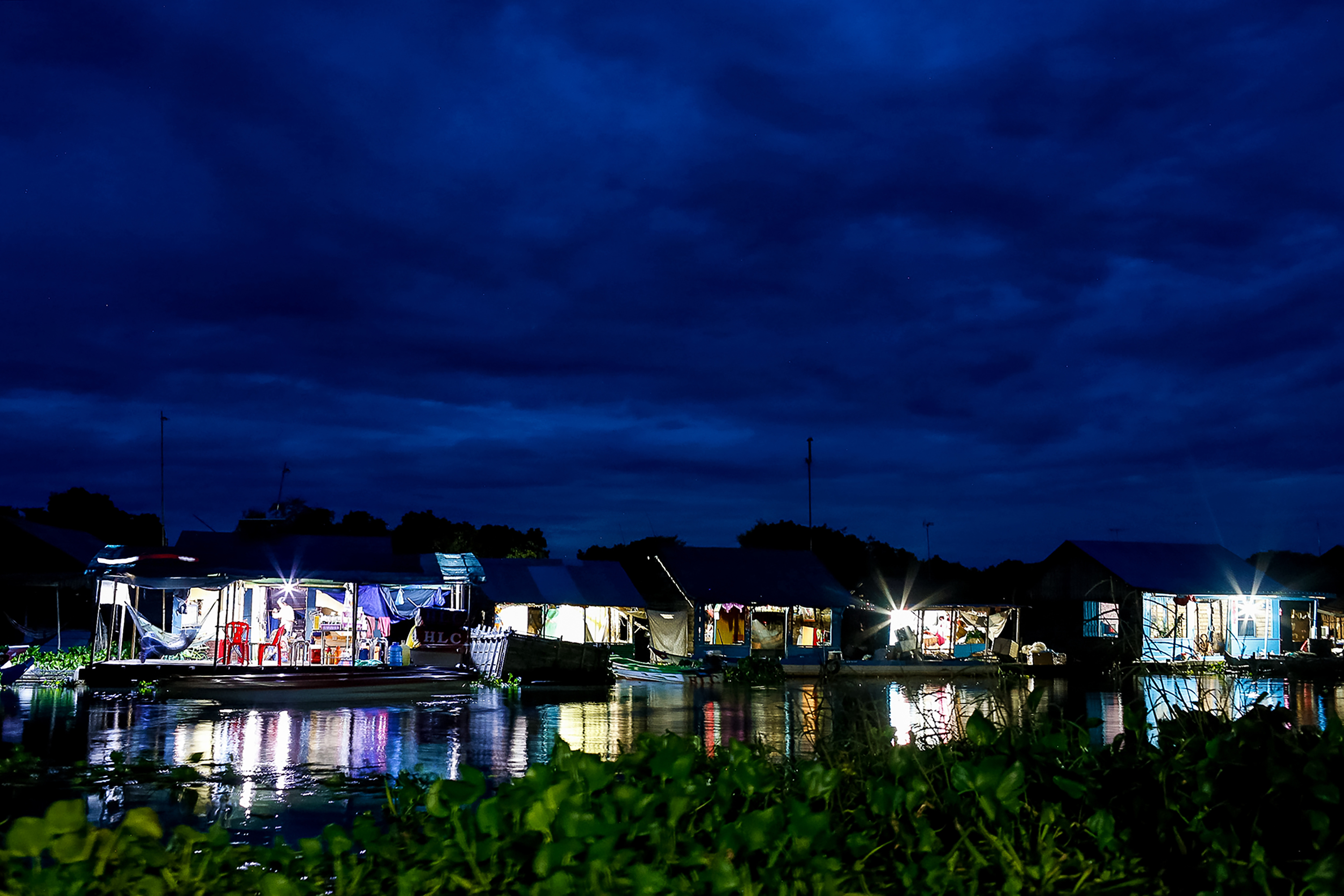 Floating homes glow with light along the water at night