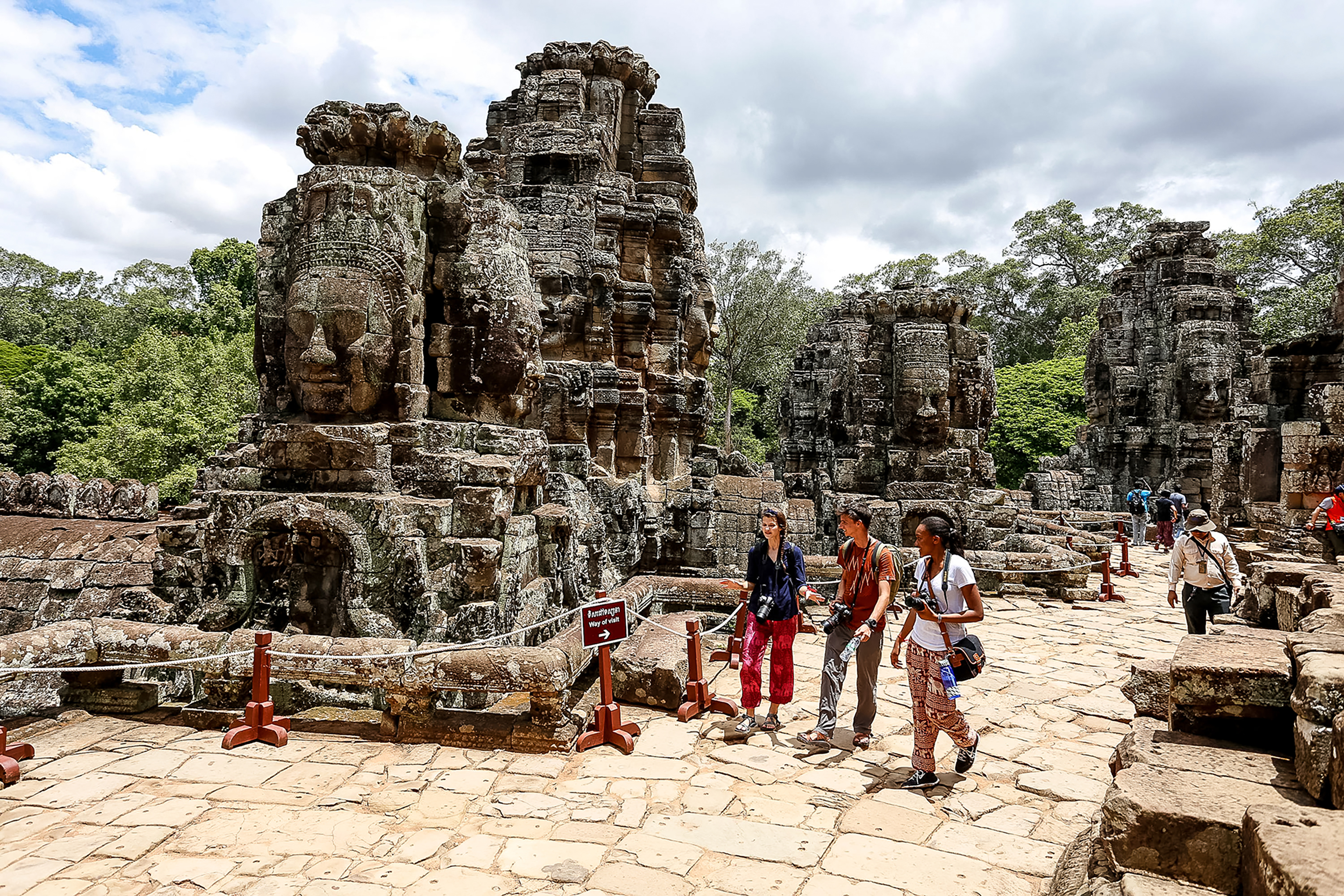 Students walk among the carved stone faces of Bayon temple