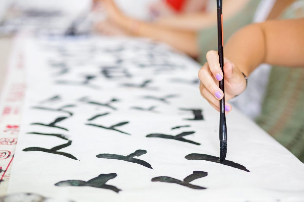 Hand painting Chinese calligraphy on white paper. Fun facts about China