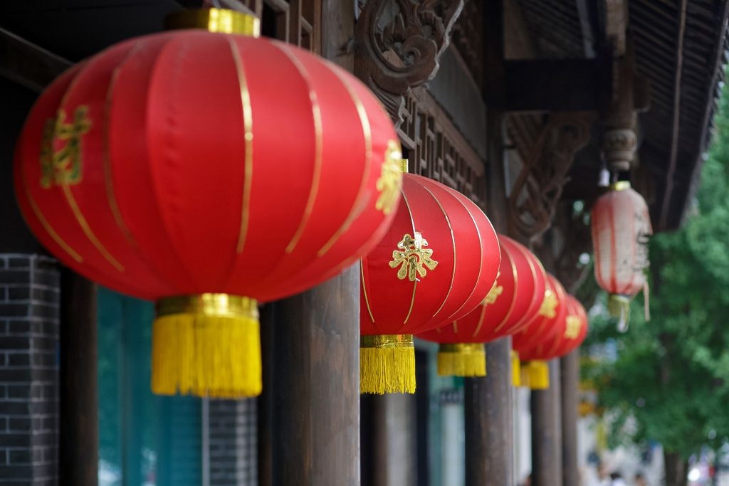 fun facts about China Row of red lanterns with yellow tassels hanging under a wooden structure. Fun facts about China