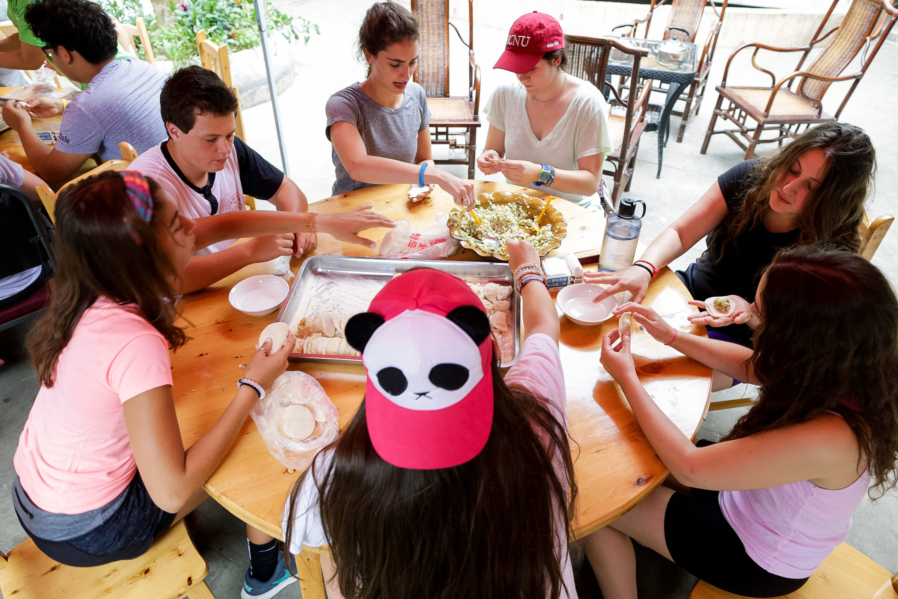 On this school trip, students gather around a table making dumplings together