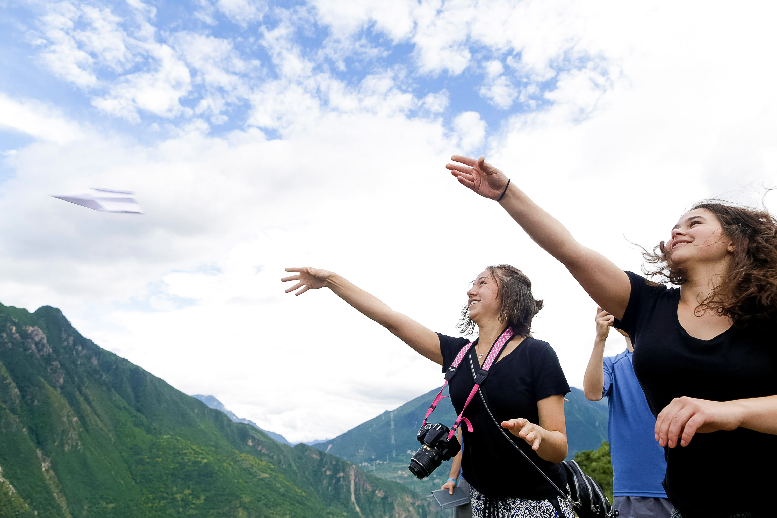 Students throw a paper airplane from a mountain overlook