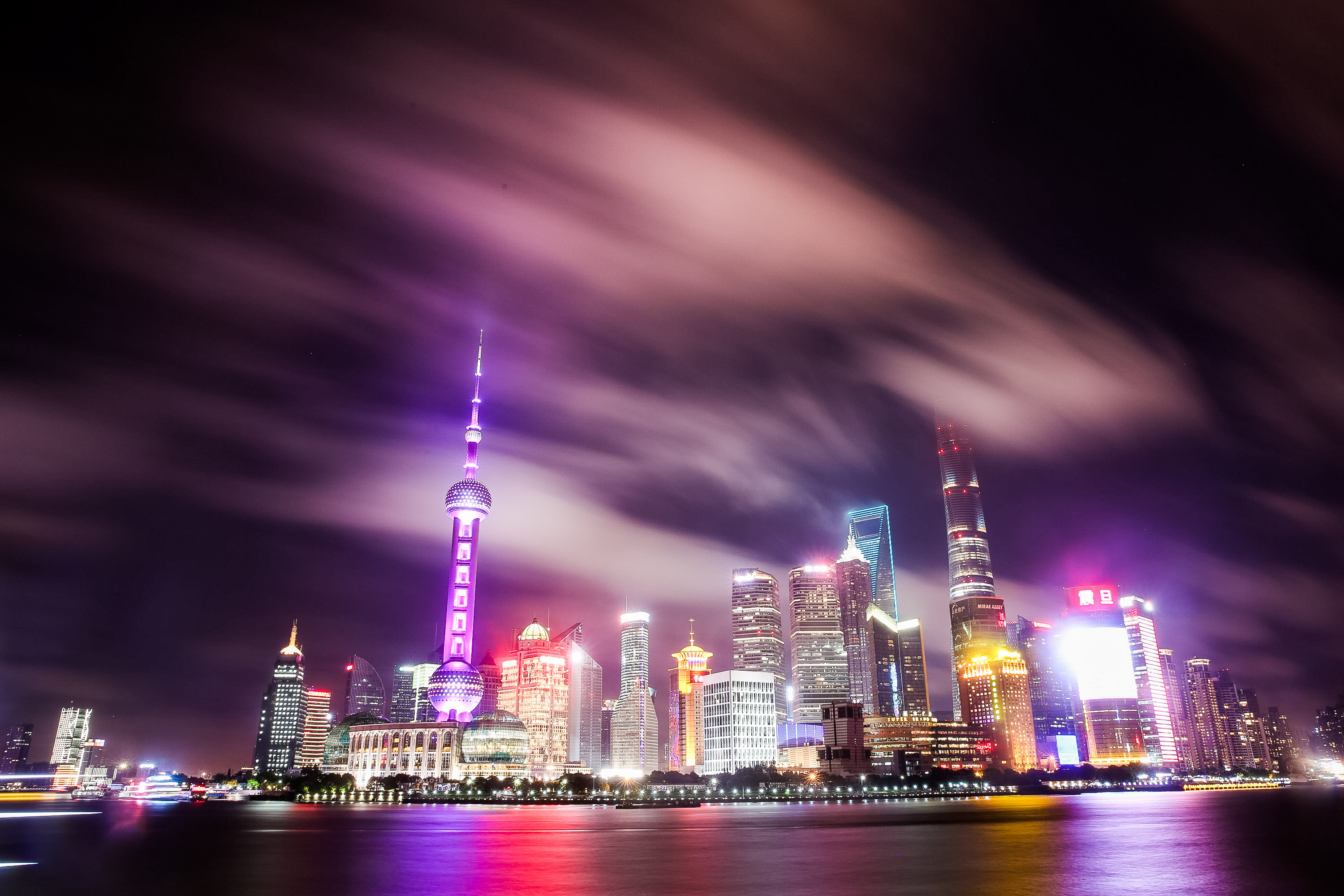 City skyline glows at night with illuminated towers reflected on the waterfront