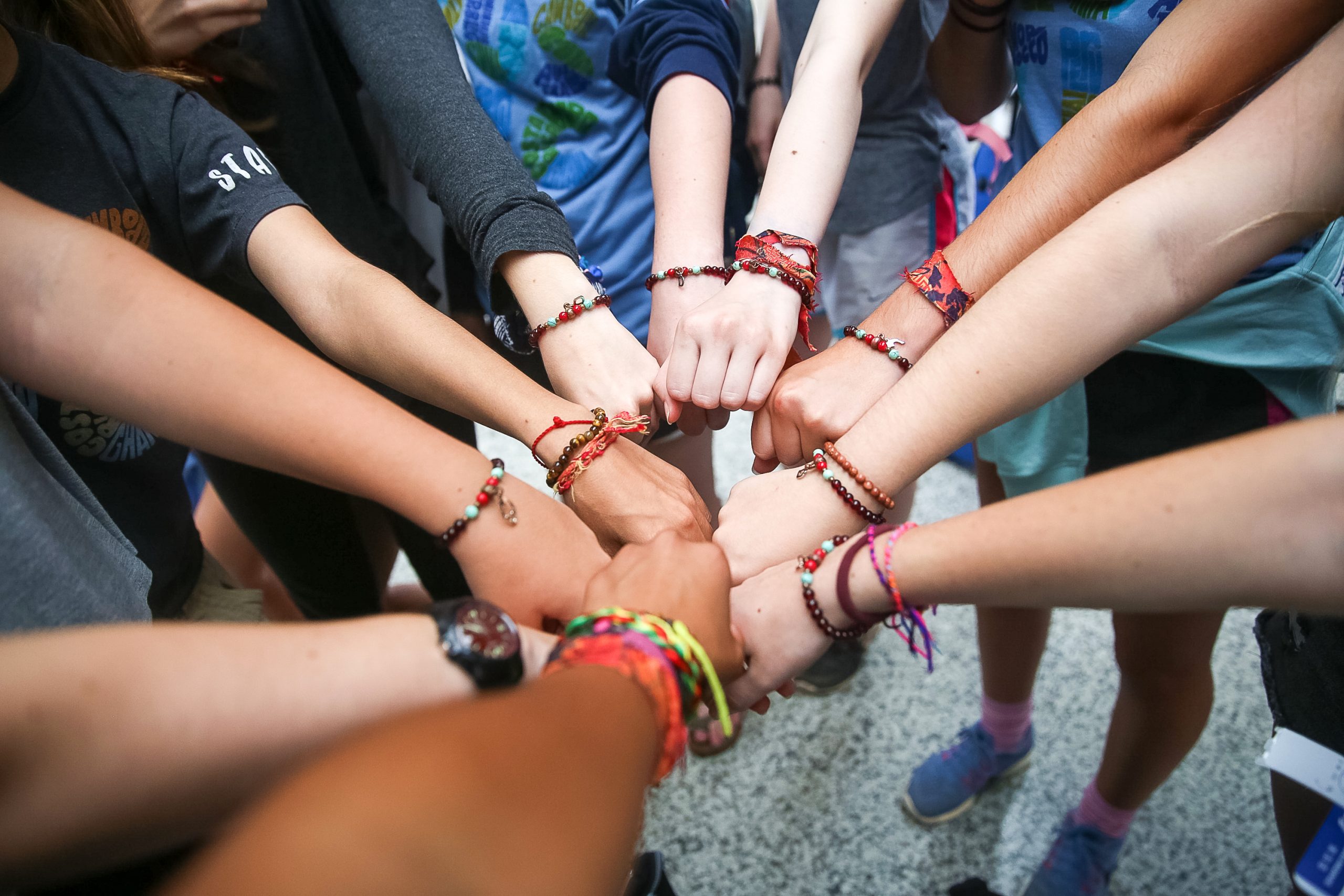 Students on a Rustic Pathways program in China holding their wrists together to show handmade Rustic Ties friendship bracelets