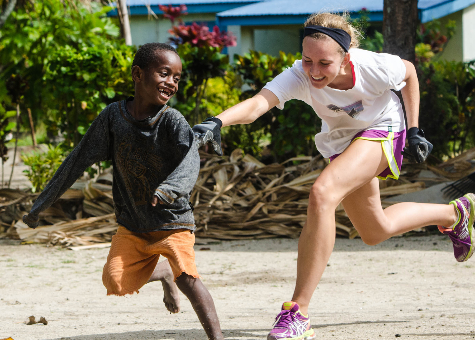 A student and a local child laugh while playing together outdoors