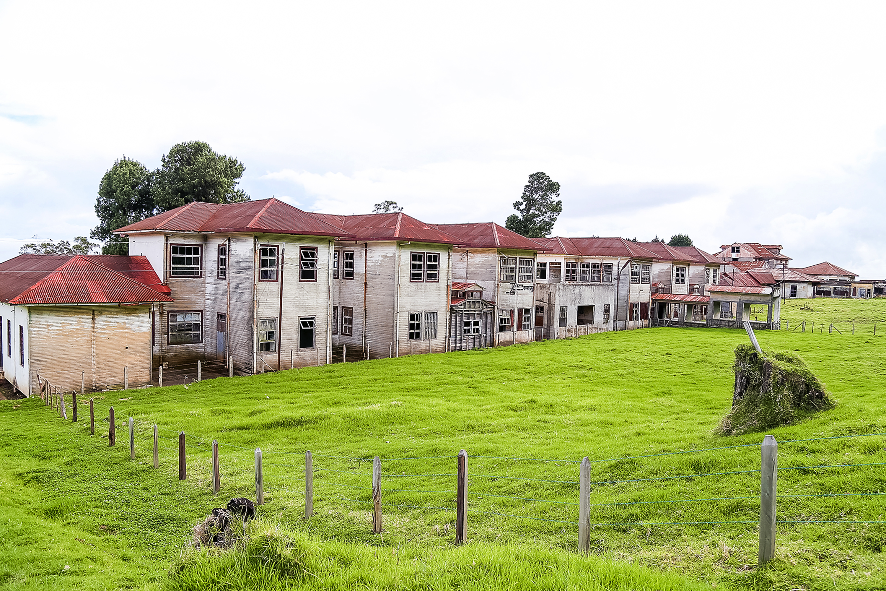 A long red-roofed building standing in an open green field