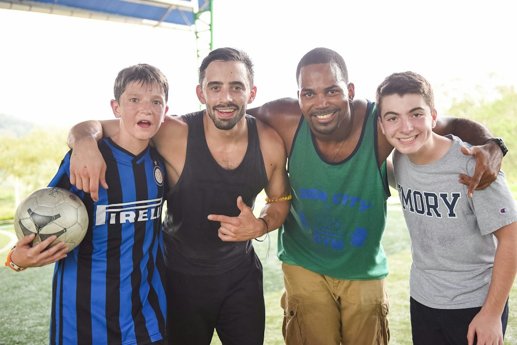 Students and mentors smiling after a soccer activity during a Rustic Pathways community volunteer program in Costa Rica, showing what volunteer abroad costs cover.