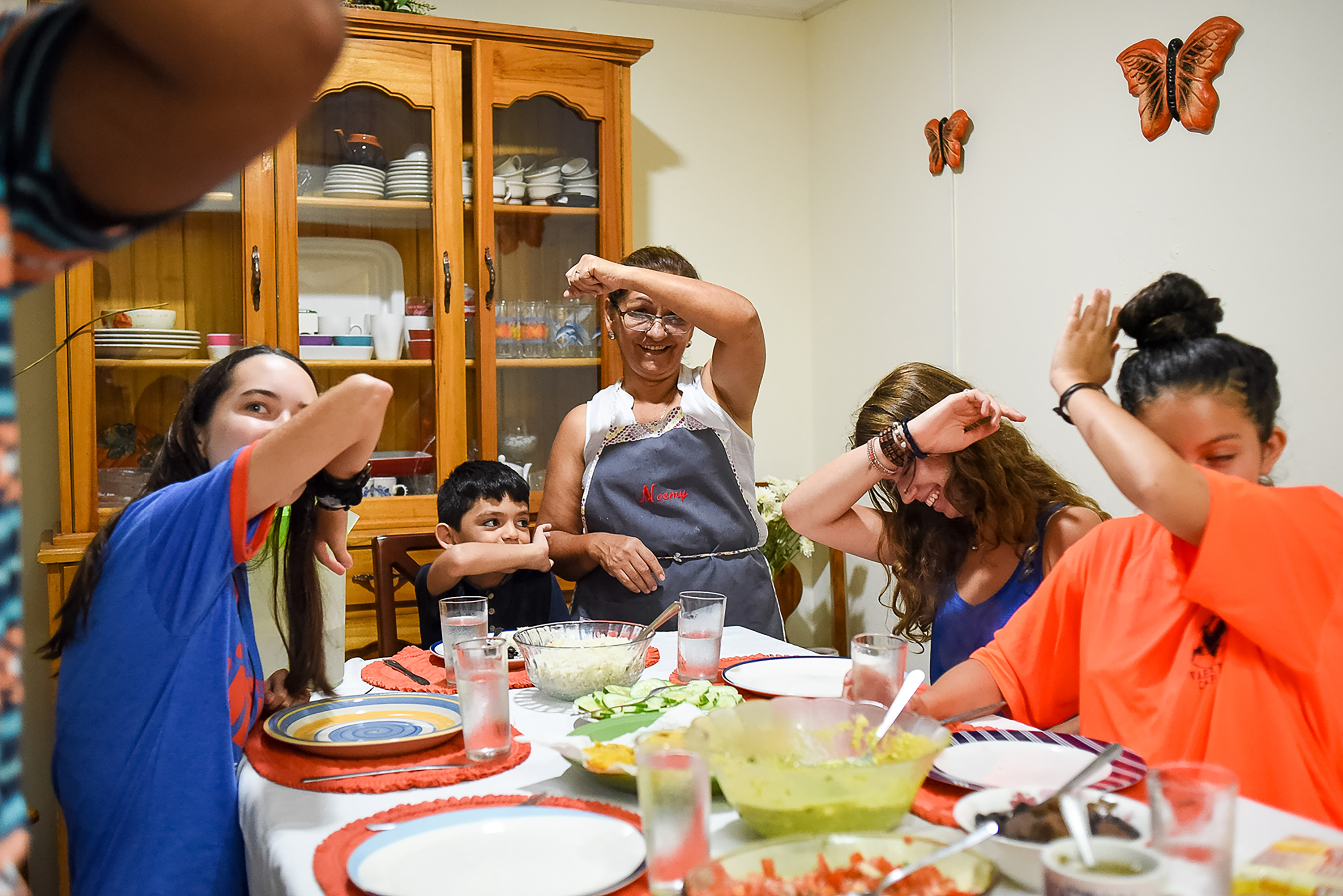 Students and a host family laughing around the dinner table
