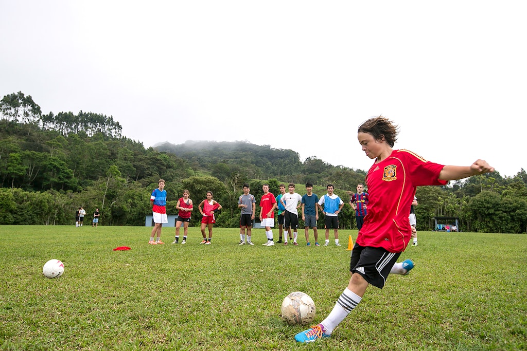A student is about to hit the soccer ball. Students support from the back.