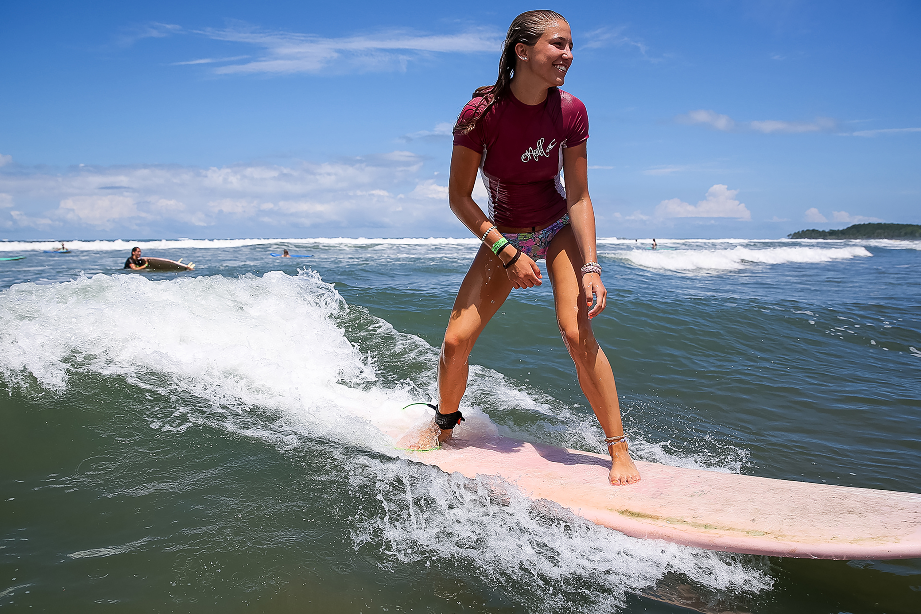 A student rides a small wave on a surfboard in Costa Rica