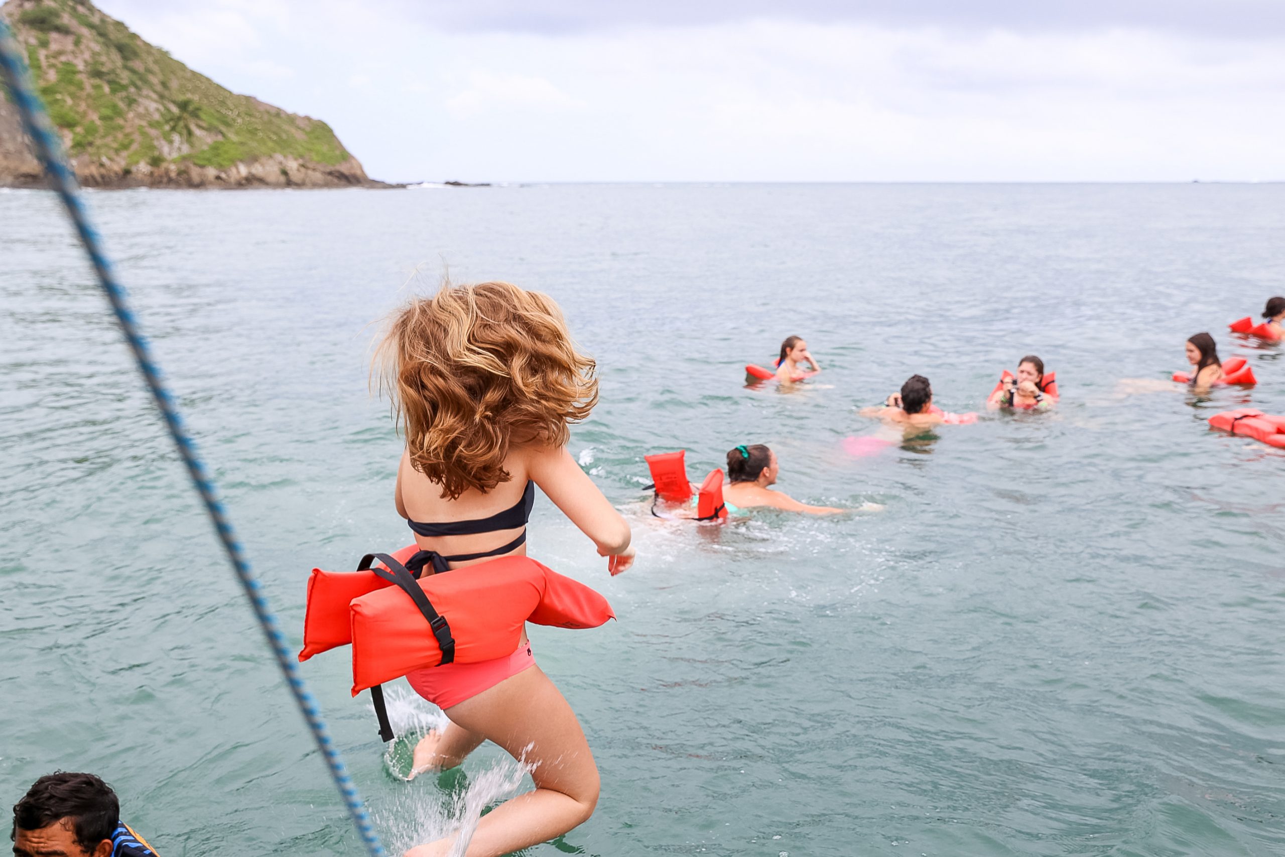 Picture of students swimming in the ocean with mountain in the background.