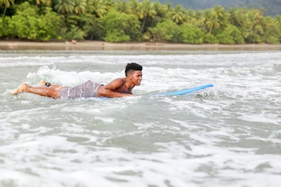 A student paddles on a surfboard during a surfing lesson in Costa Rica on a summer teen tour