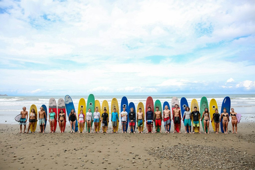 Large school group volunteer abroad programs group lined up with surfboards after service and cultural activities.