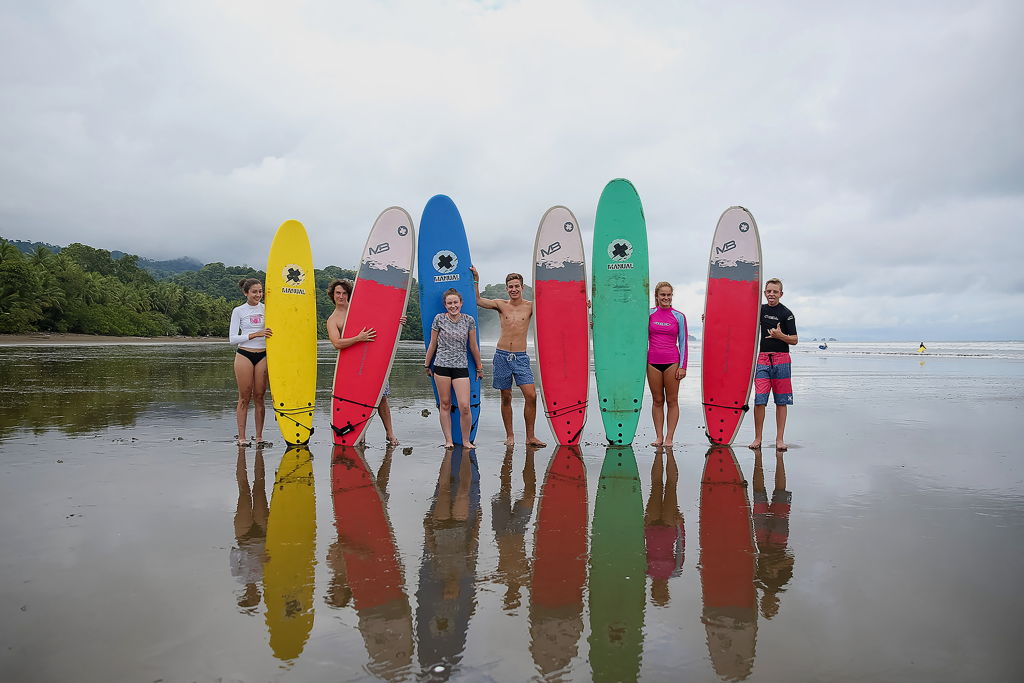 Rustic Pathways teen travelers with surfboards on a beach during a summer program for high school students in Costa Rica.