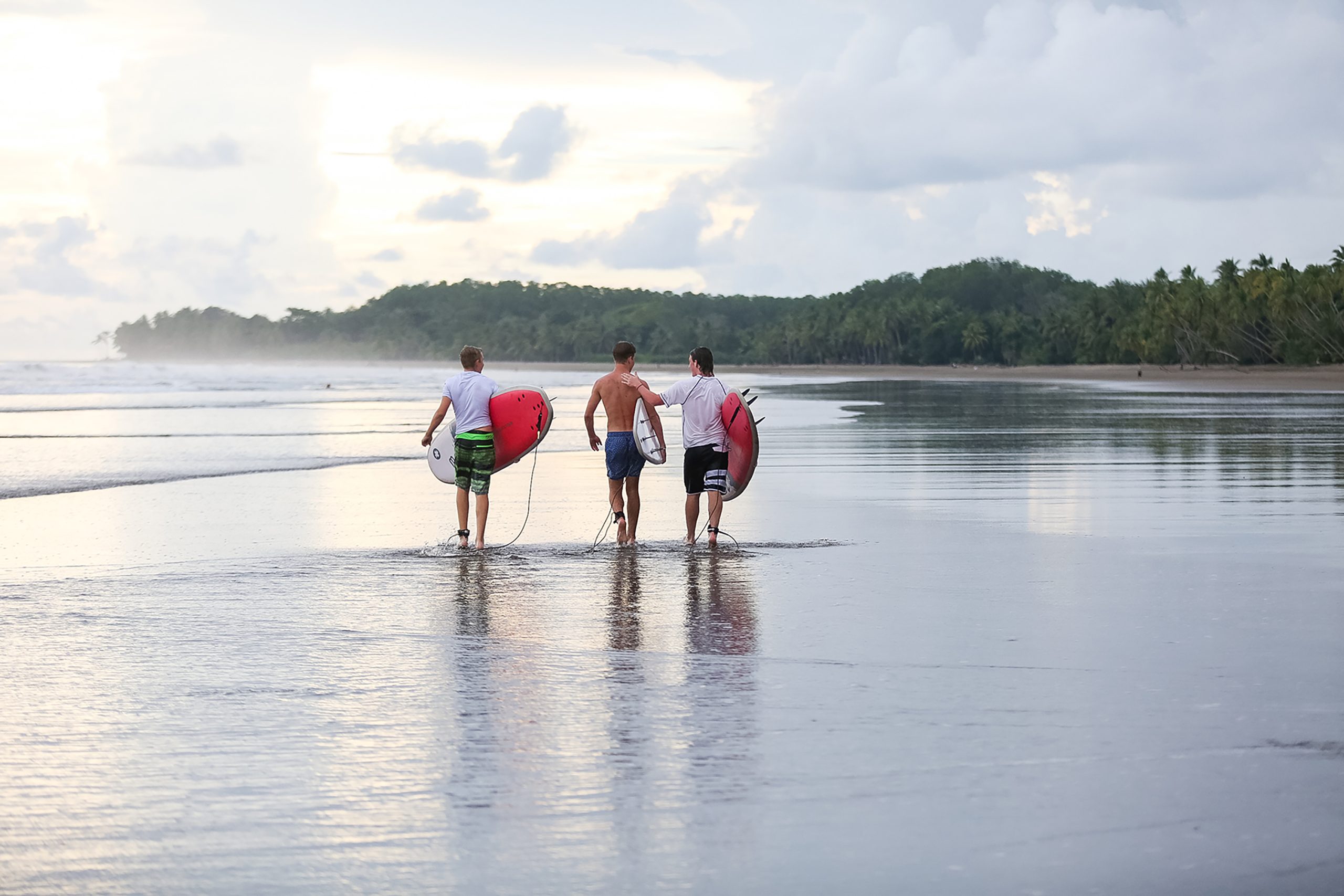 Surfers walking on a Costa Rican beach at sunset