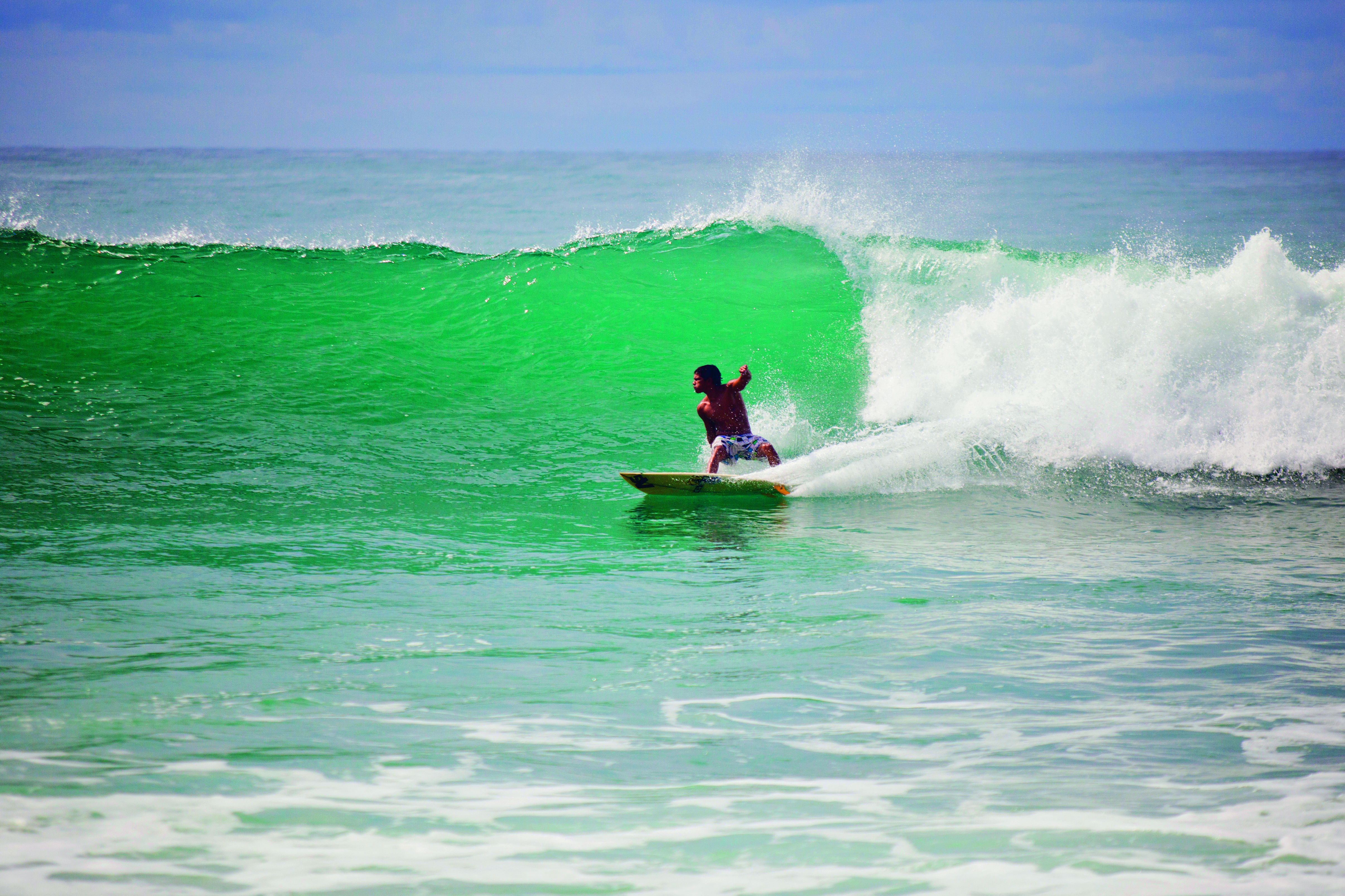 A surfer rides a breaking wave along the Kona coast