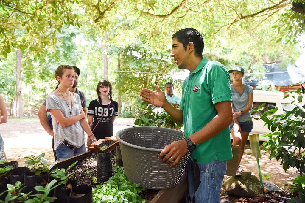 Picture of students gathered around a man who is giving instructions at a garden.