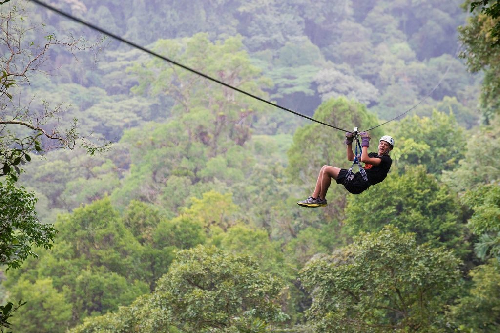 Teen enjoying ziplining through the lush canopy of Costa Rica's rainforest.